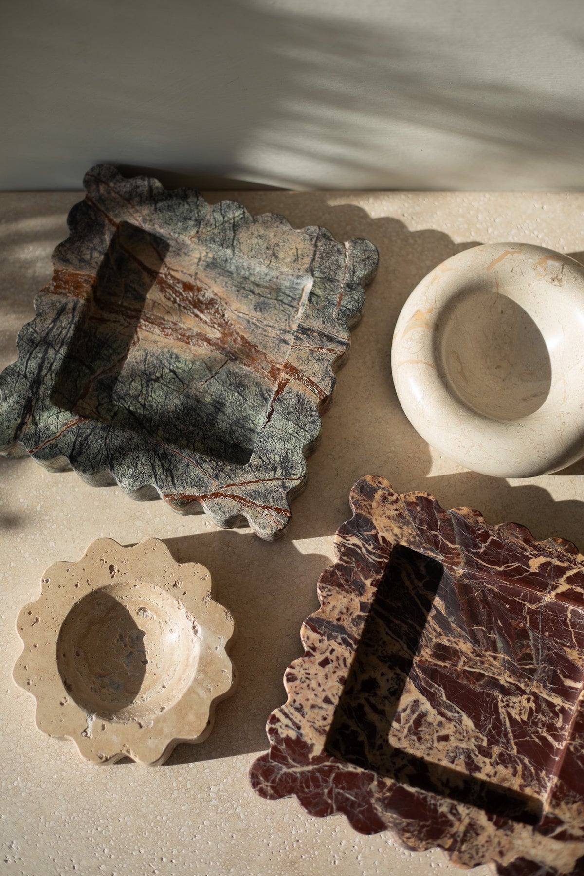 The Mini Sun Scoop Travertine by Anastasio Home, handcrafted from a single piece of solid marble stone. This decorative tray features a unique design and natural stone variations, perfect for your coffee table or vanity.