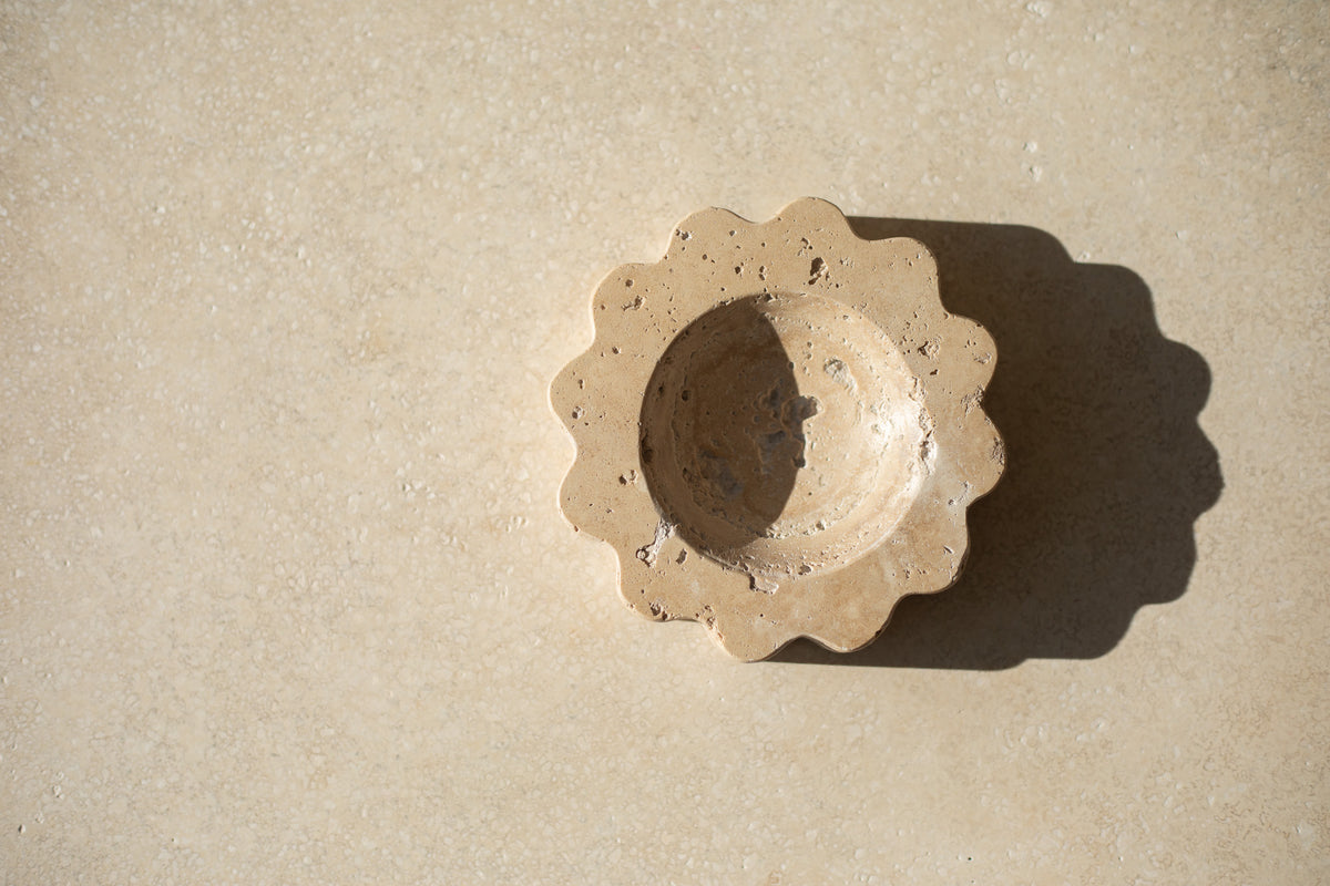 The Mini Sun Scoop Travertine by Anastasio Home, handcrafted from a single piece of solid marble stone. This decorative tray features a unique design and natural stone variations, perfect for your coffee table or vanity.