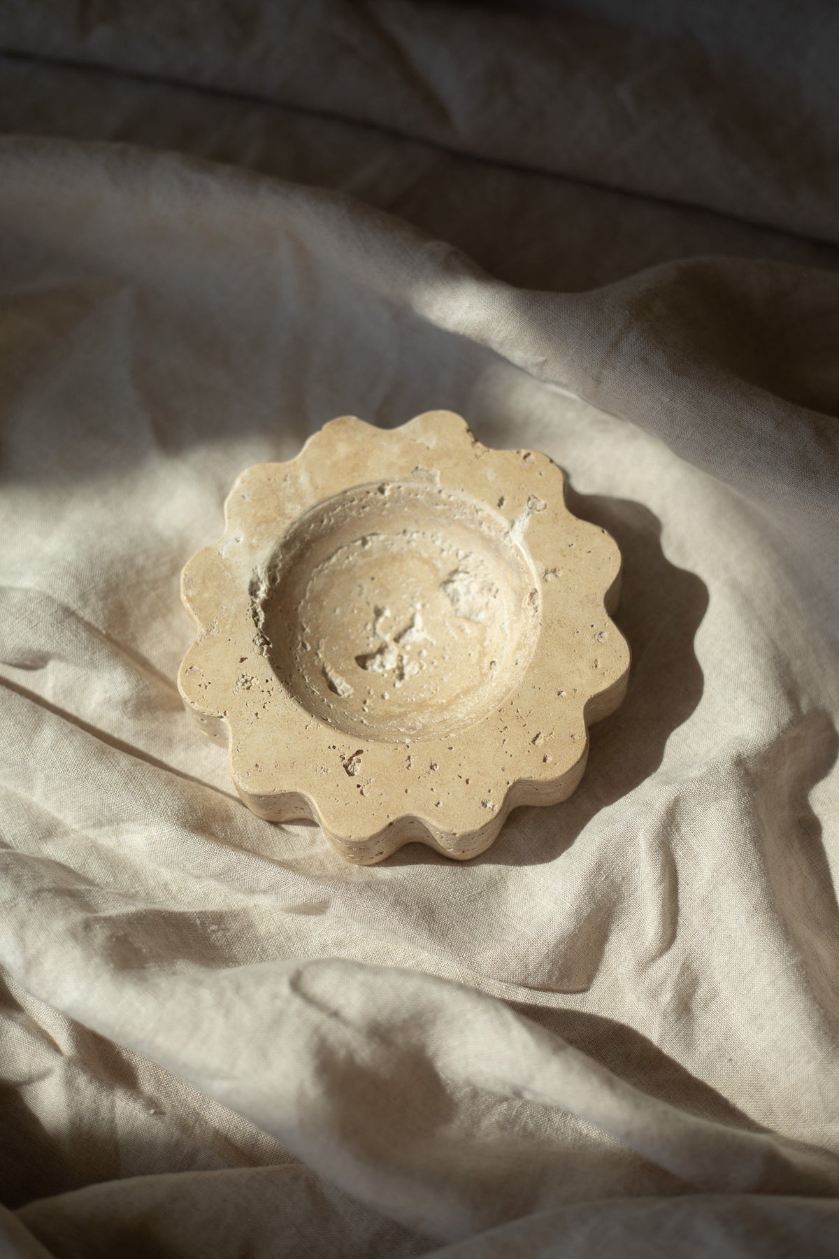 The Mini Sun Scoop Travertine by Anastasio Home, handcrafted from a single piece of solid marble stone. This decorative tray features a unique design and natural stone variations, perfect for your coffee table or vanity.