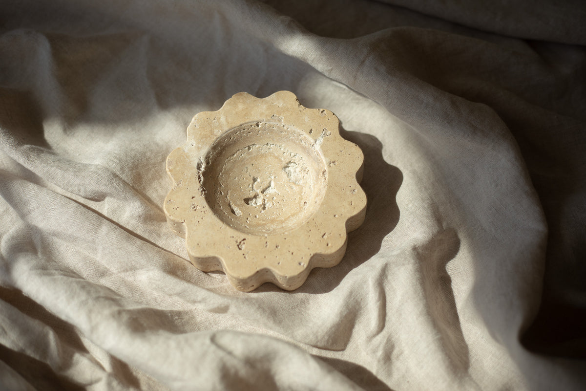 The Mini Sun Scoop Travertine by Anastasio Home, handcrafted from a single piece of solid marble stone. This decorative tray features a unique design and natural stone variations, perfect for your coffee table or vanity.