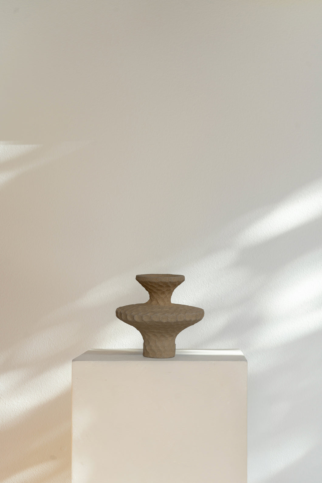 Corner II minimalist ceramic sculpture, two circular discs with tapered neck and textured surface, inspired by ancient ritual vessels.