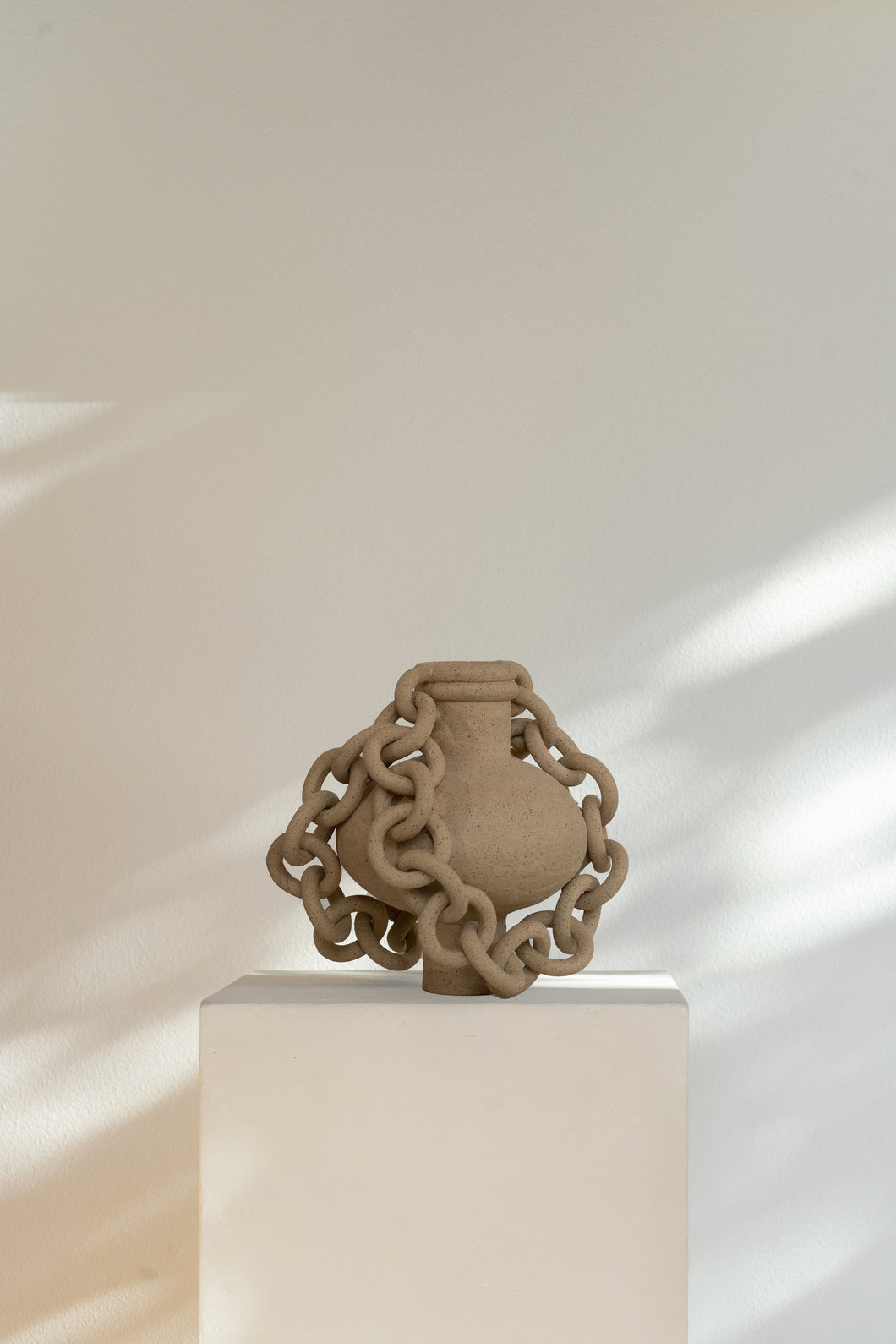 Double-chained ceramic vessel with sculptural design, modern decor accent piece with bold statement.