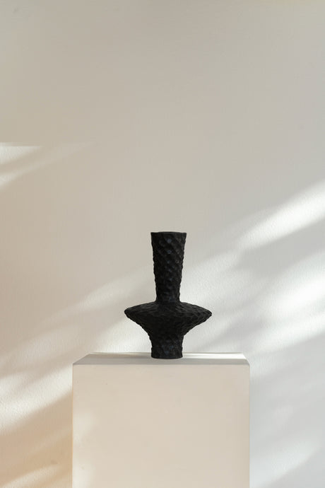 Matte black Corner I Vessel, ceramic sculpture with textured circular base and narrow neck, tactile raised bumps.