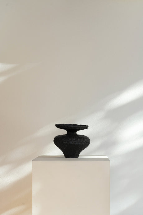 Minimalist Corner III ceramic sculpture, deep matte black with two circular discs and tapered neck, bold and modern design.