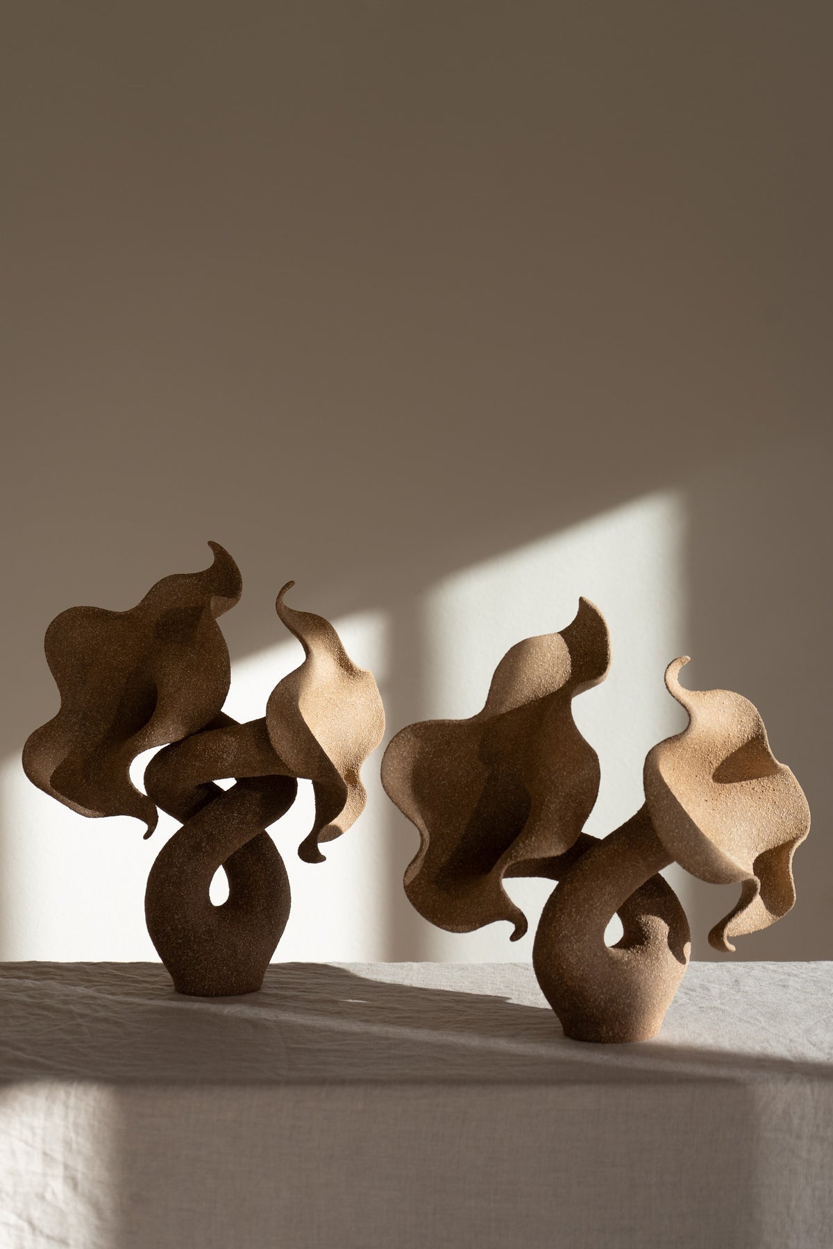 A striking piece of ceramic art, featuring a soft, seductive shell contrasted with raw, coarse textures. The vessel, crafted from textured matte grog stoneware with a brown exterior and glazed interior, evokes a dramatic allure and delicate inner essence. 