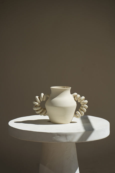 A whimsical and limited-edition ceramic piece with spring-inspired handles. Handcrafted by Kassandra Guzman, this unique vase features playful curves and is perfect for adding energy and movement to any space.