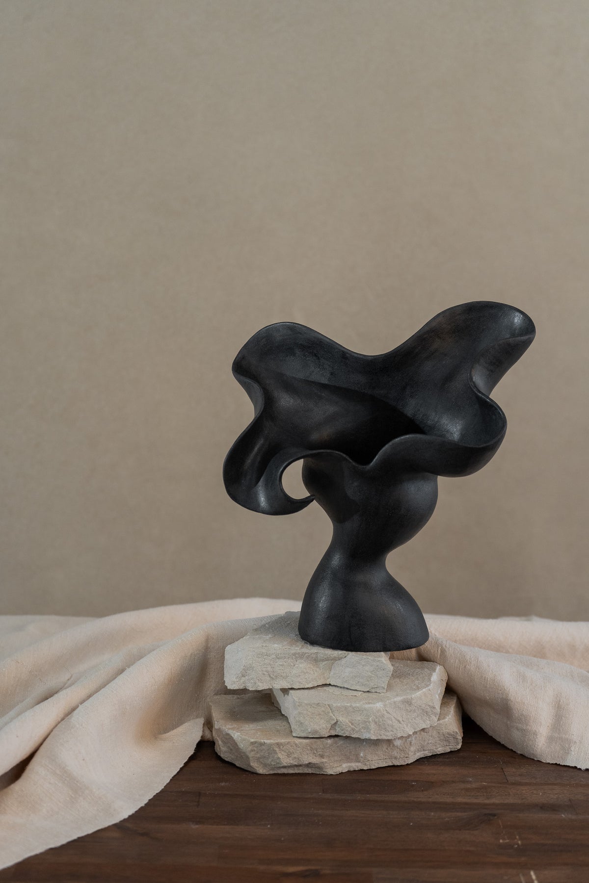 This matte black, textured ceramic vessel embodies the lifecycle of a flower, showcasing nature's beauty from bloom to decay. A striking statement piece for any home decor.