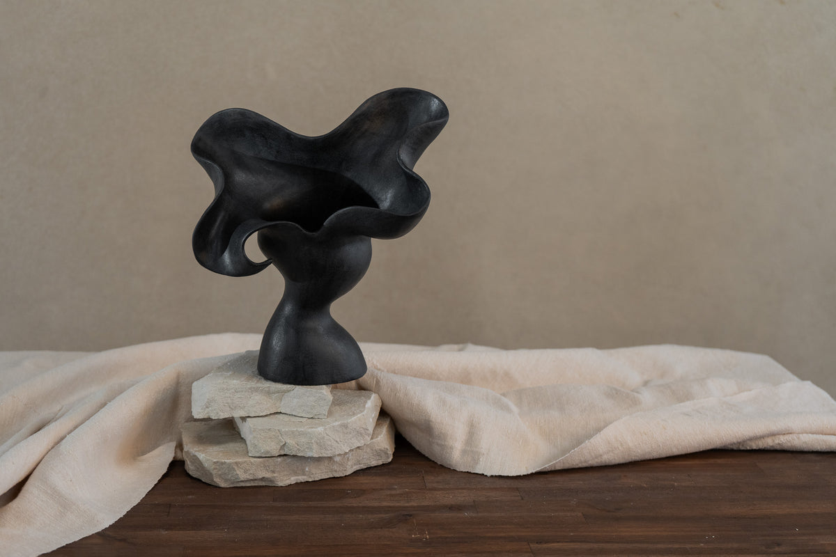 This matte black, textured ceramic vessel embodies the lifecycle of a flower, showcasing nature's beauty from bloom to decay. A striking statement piece for any home decor.