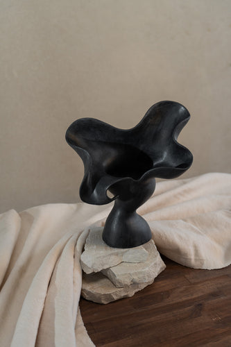 This matte black, textured ceramic vessel embodies the lifecycle of a flower, showcasing nature's beauty from bloom to decay. A striking statement piece for any home decor.