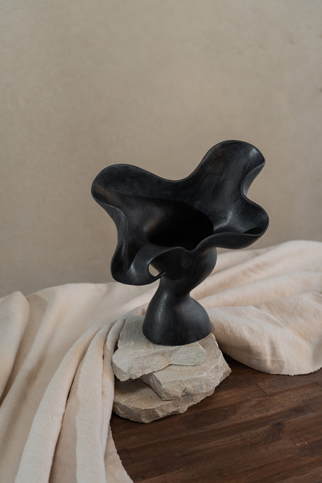 This matte black, textured ceramic vessel embodies the lifecycle of a flower, showcasing nature's beauty from bloom to decay. A striking statement piece for any home decor.