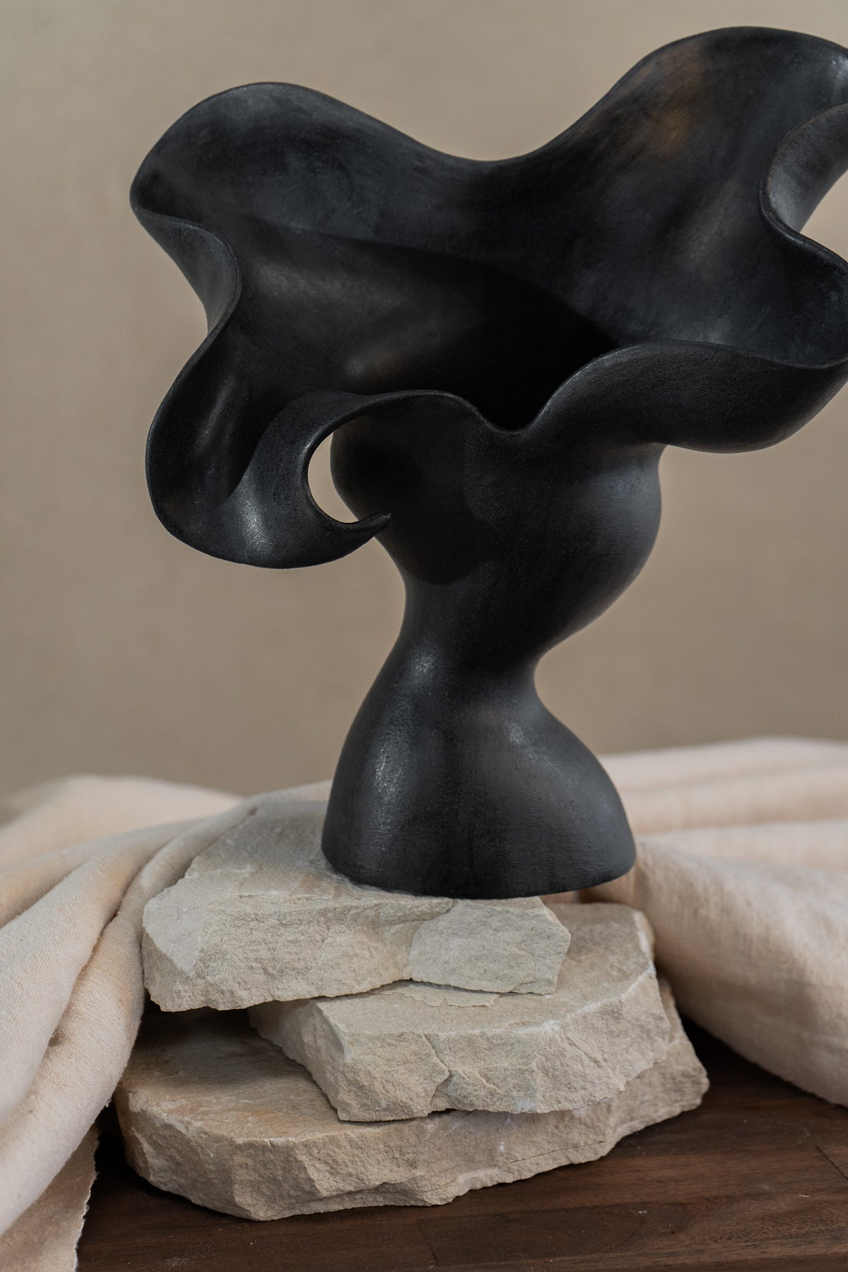 This matte black, textured ceramic vessel embodies the lifecycle of a flower, showcasing nature's beauty from bloom to decay. A striking statement piece for any home decor.