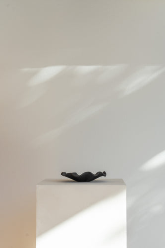 A low handmade ceramic tray with a wavy edge. The tray has a light brown, slightly textured surface 