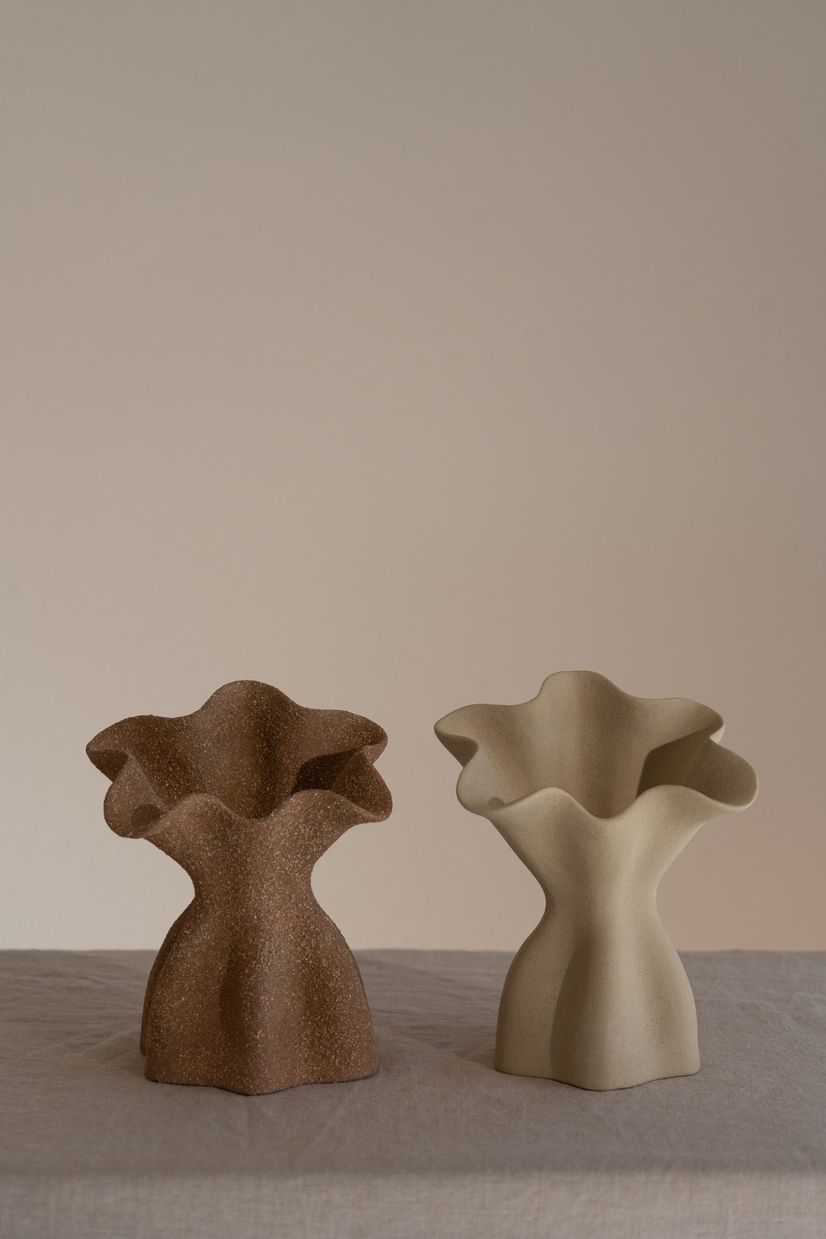 A beautifully crafted matte taupe ceramic vase with soft, organic shapes and a glazed interior. 