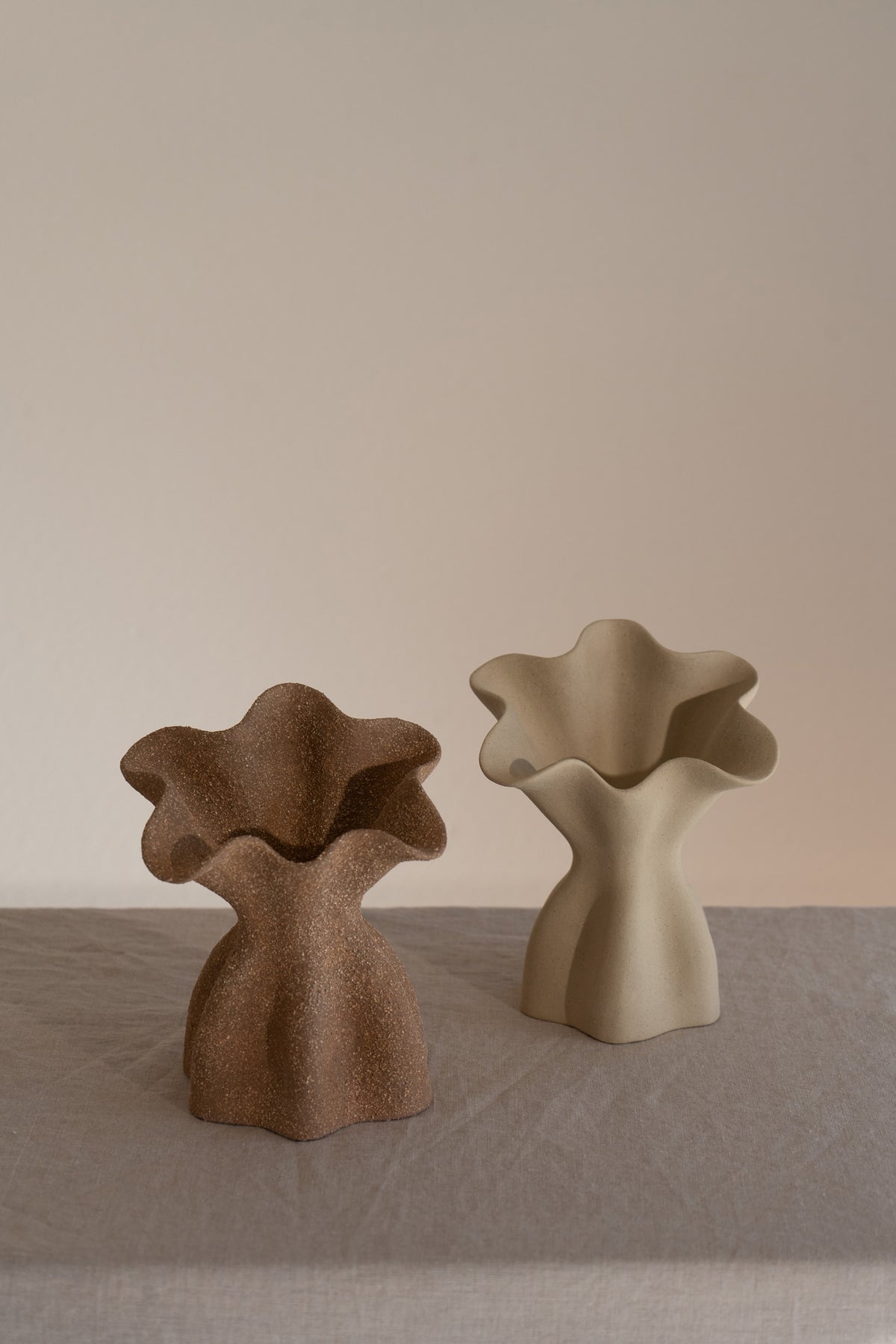 A beautifully crafted matte taupe ceramic vase with soft, organic shapes and a glazed interior. 