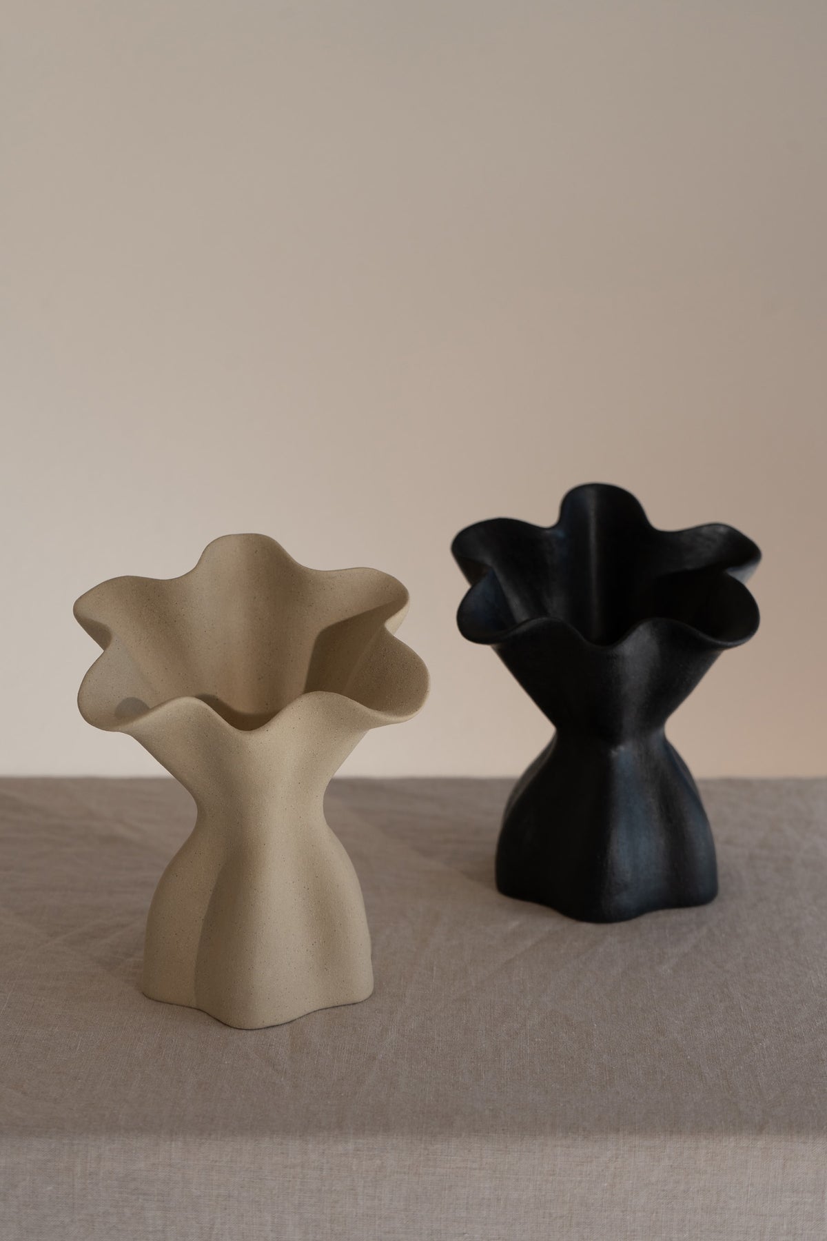 A beautifully crafted matte black ceramic vase with soft, organic shapes and a glazed interior. 