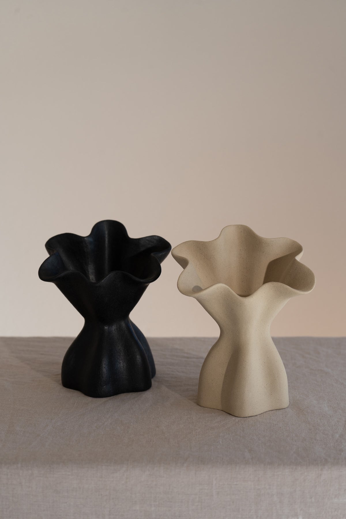 A beautifully crafted matte black ceramic vase with soft, organic shapes and a glazed interior. 