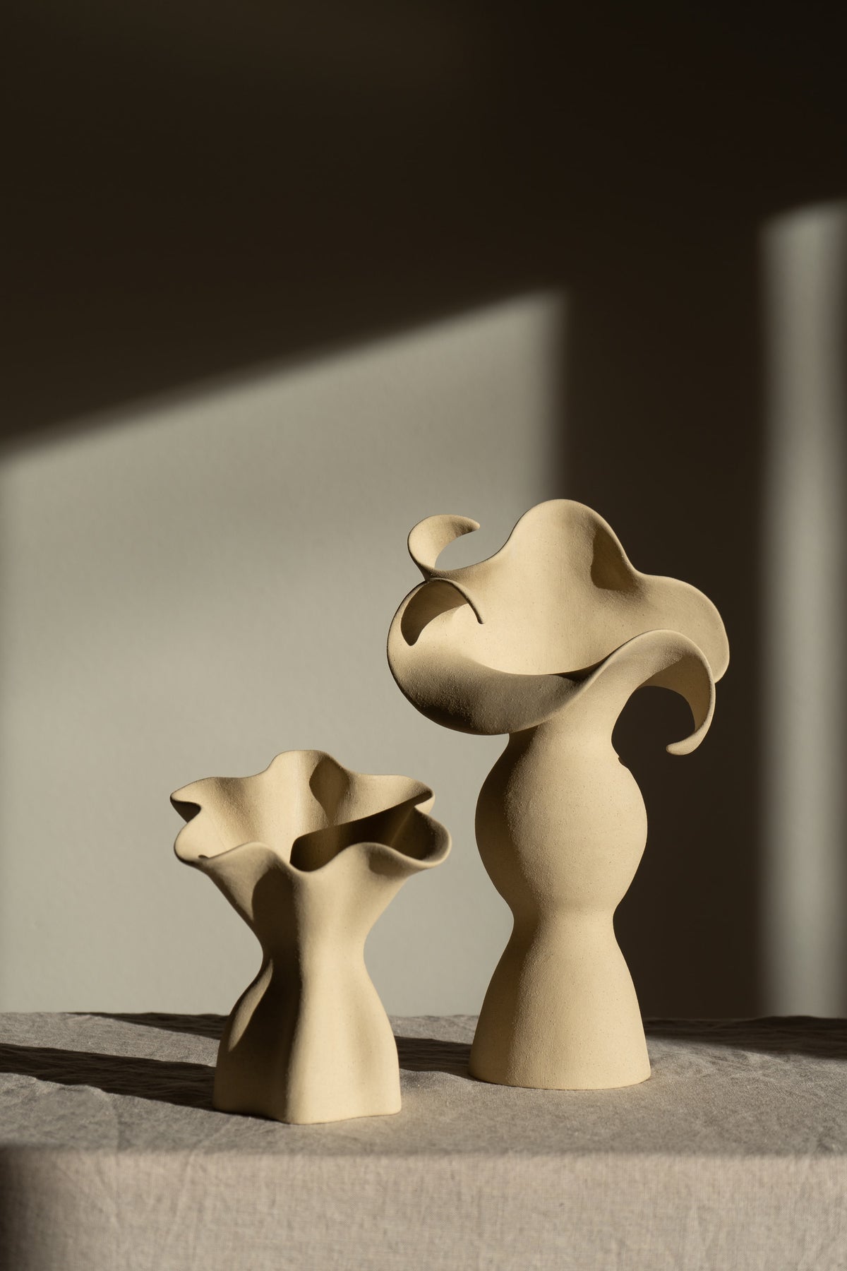 A beautifully crafted matte taupe ceramic vase with soft, organic shapes and a glazed interior. 