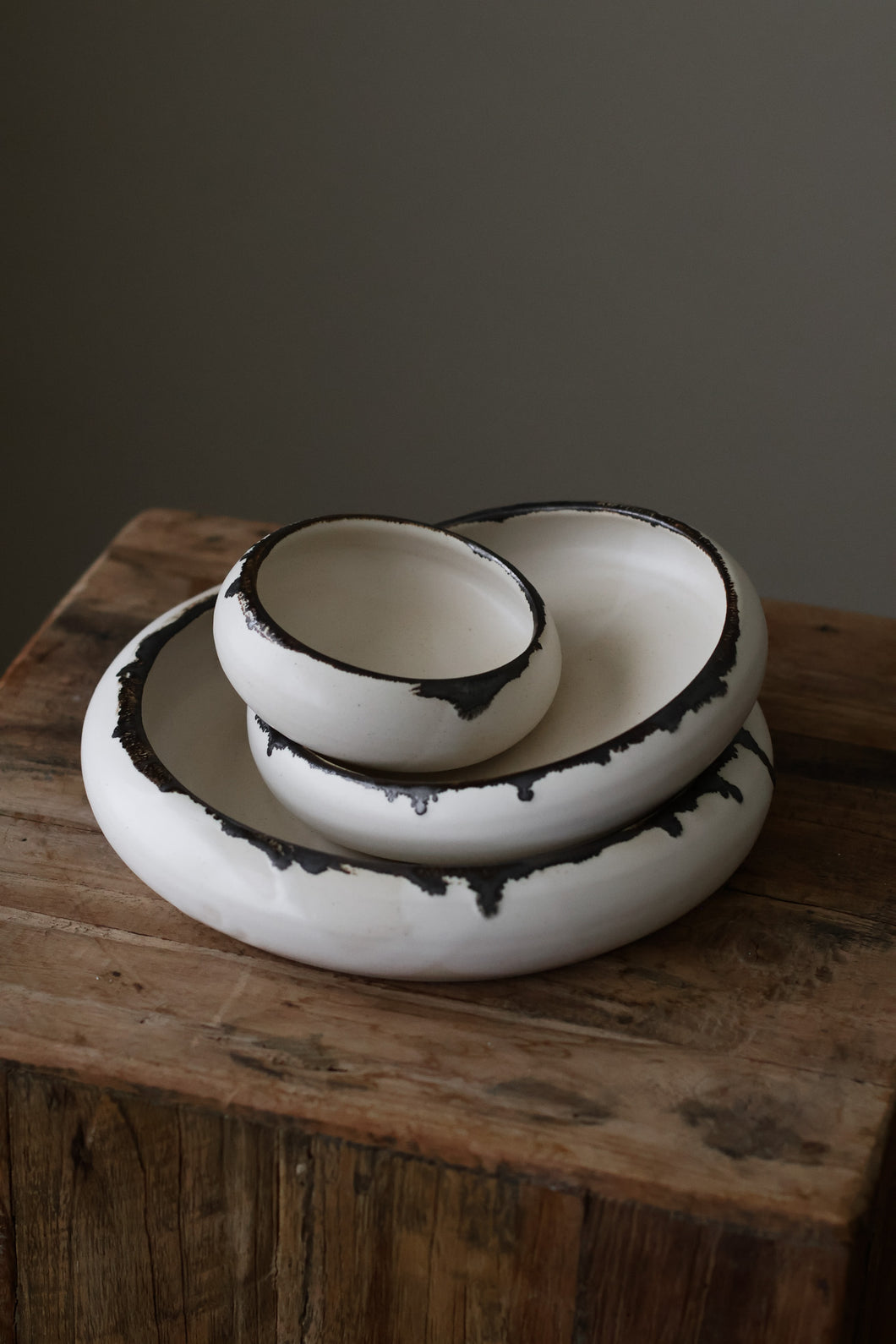 Crescent Plate Porcelain is crafted in cream with a bold, dark rim detailing that evokes a sense of lunar movement. Each plate is a part of a nesting set, designed to create harmony whether used individually or layered together.