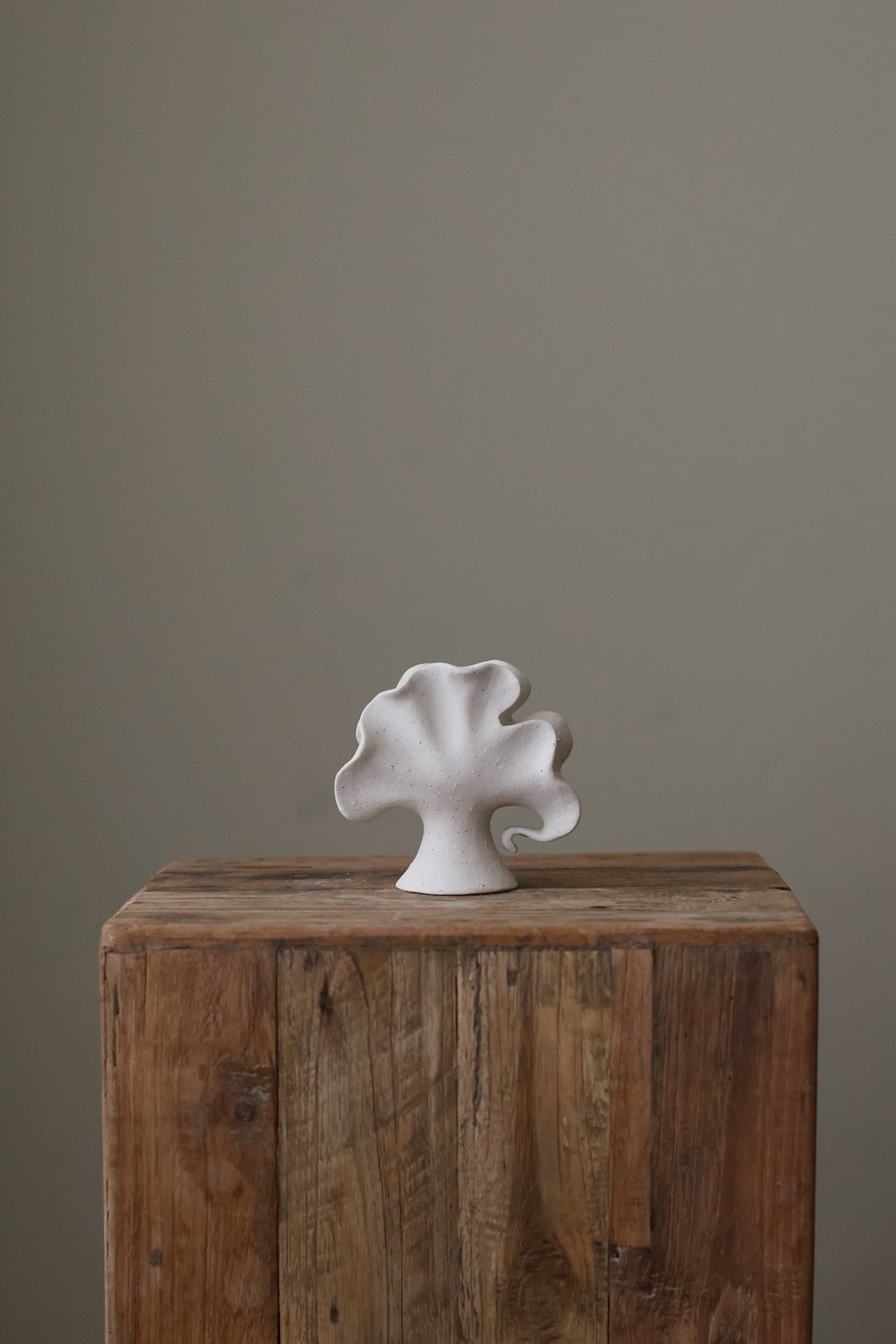 Leaf Vessel is a small handmade ceramic vase with sculptural ruffled design and matte white speckled finish, featuring an abstract organic shape.