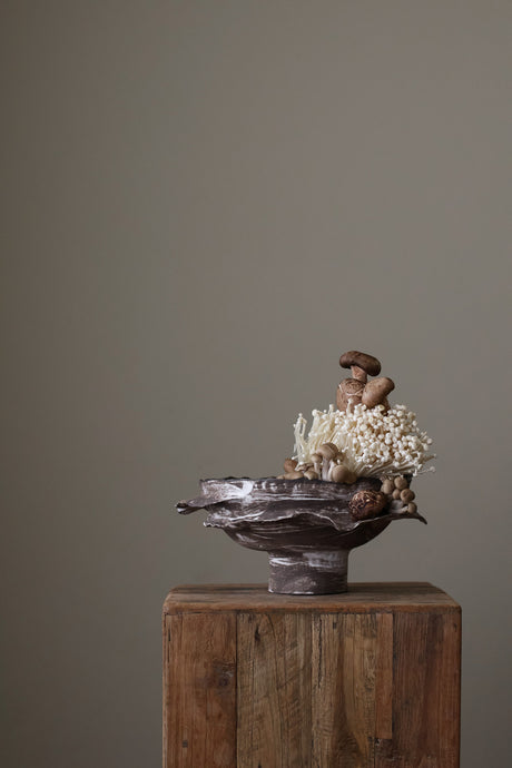 Layered Brown Pedestal Bowl is a Handcrafted ceramic piece with raw, textured dark clay finish and organic wavy rim, featuring sculptural asymmetry