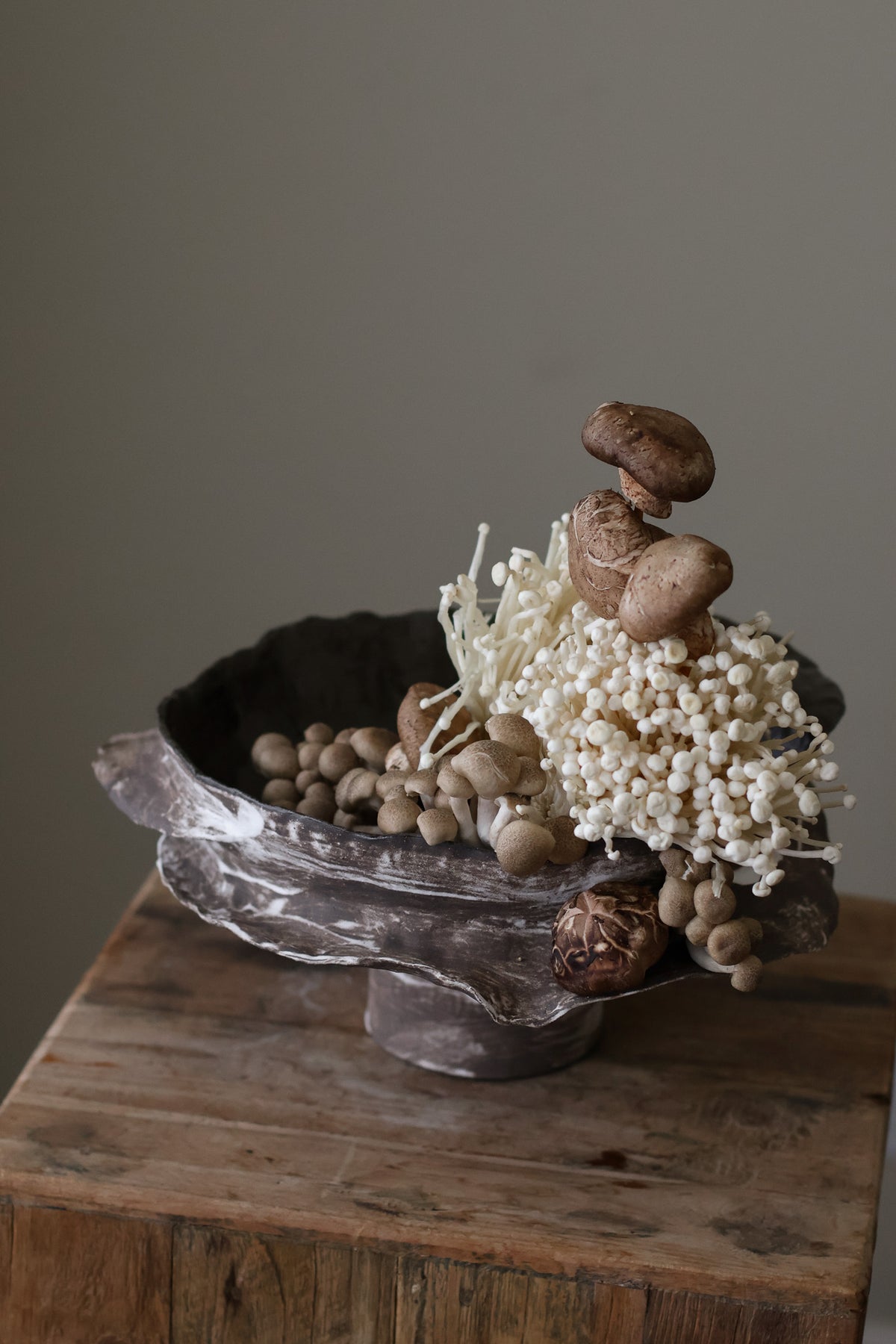 Layered Brown Pedestal Bowl is a Handcrafted ceramic piece with raw, textured dark clay finish and organic wavy rim, featuring sculptural asymmetry