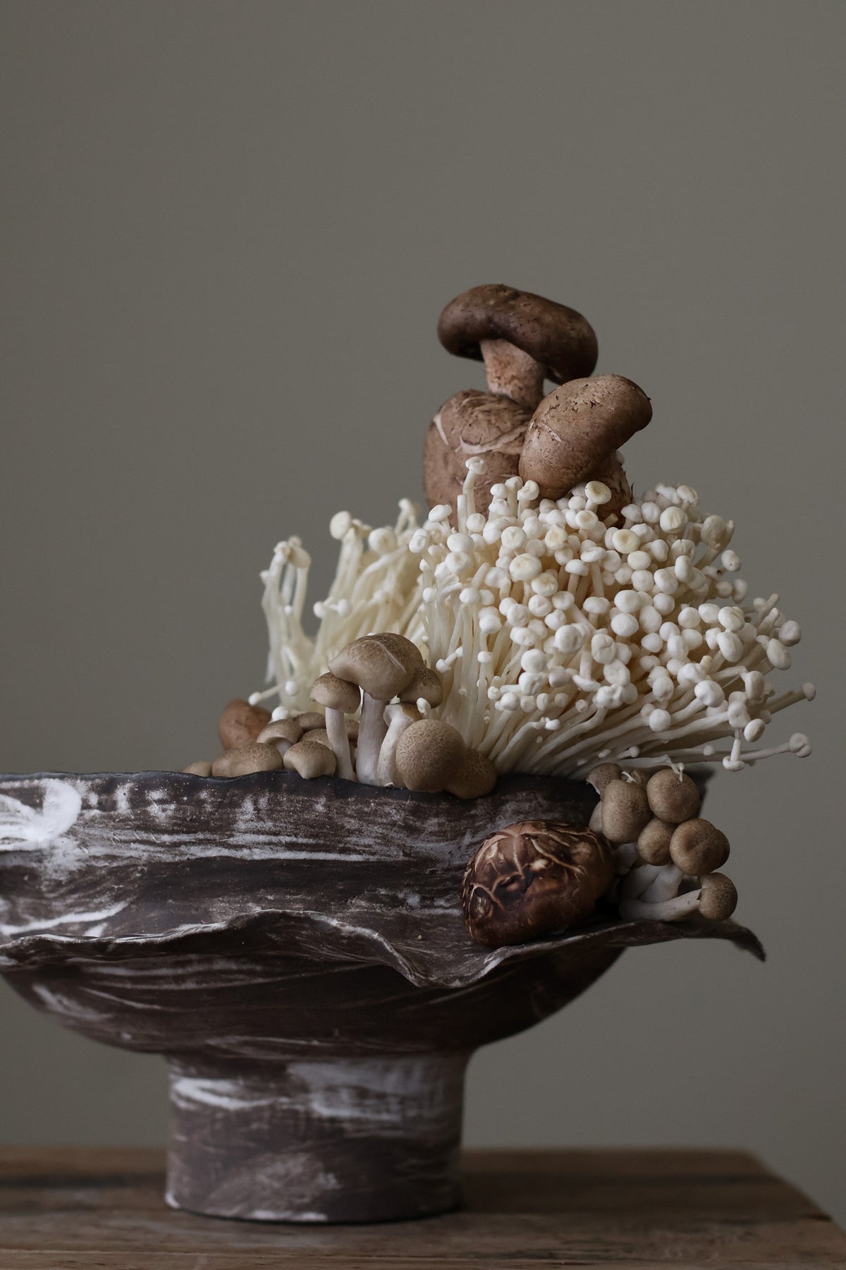 Layered Brown Pedestal Bowl is a Handcrafted ceramic piece with raw, textured dark clay finish and organic wavy rim, featuring sculptural asymmetry