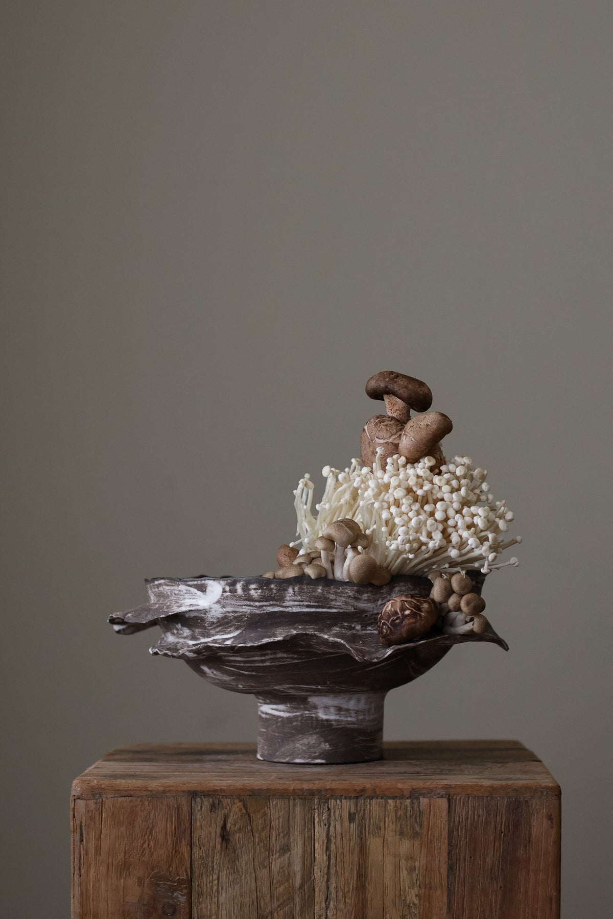 Layered Brown Pedestal Bowl is a Handcrafted ceramic piece with raw, textured dark clay finish and organic wavy rim, featuring sculptural asymmetry