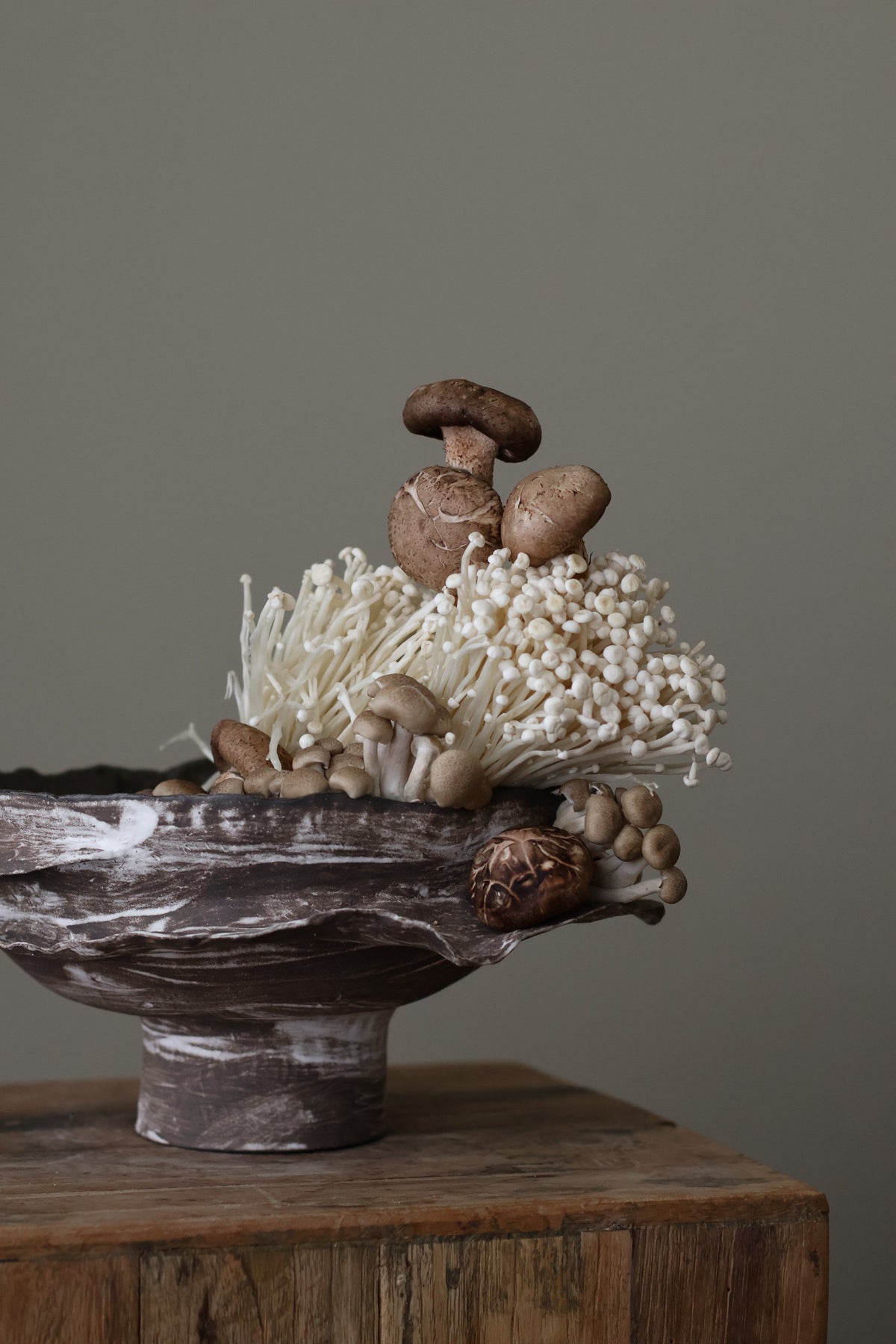 Layered Brown Pedestal Bowl is a Handcrafted ceramic piece with raw, textured dark clay finish and organic wavy rim, featuring sculptural asymmetry
