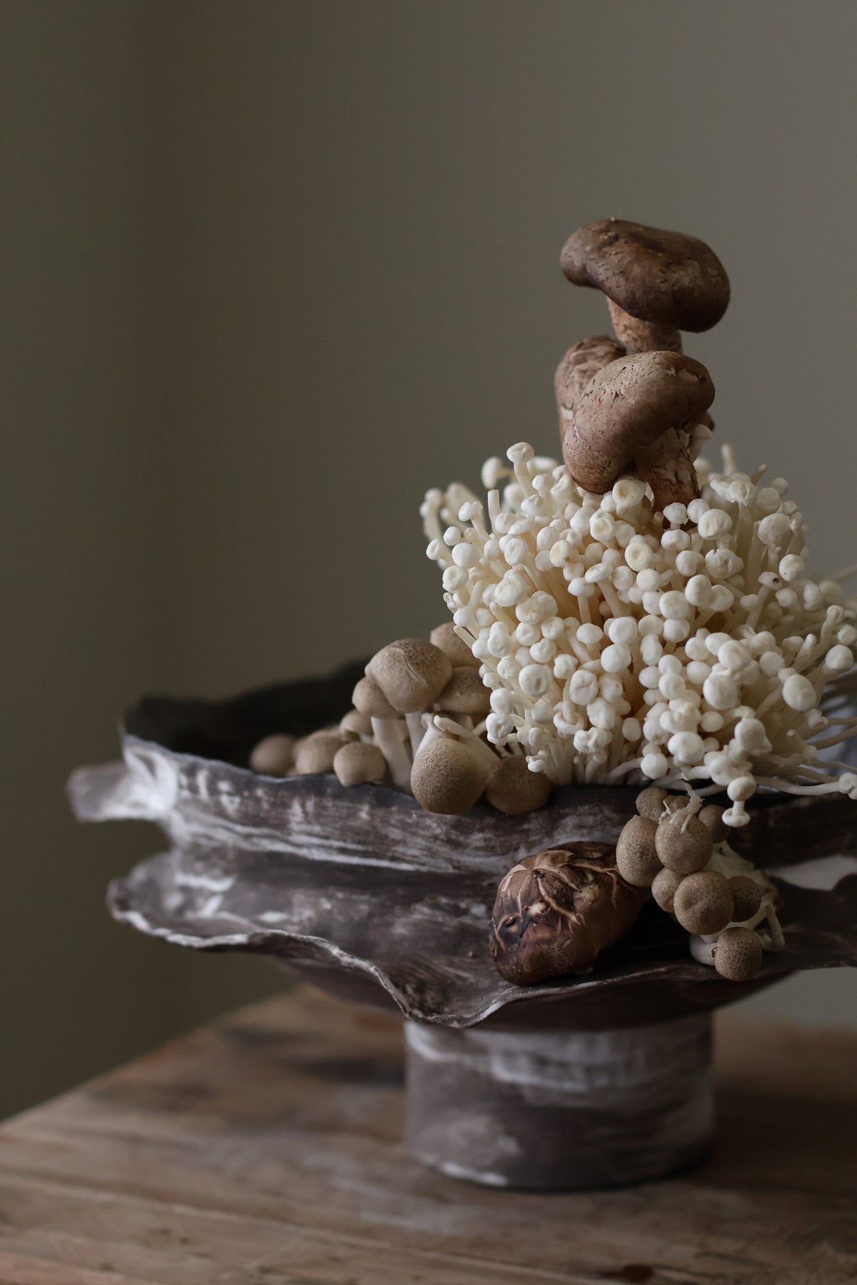 Layered Brown Pedestal Bowl is a Handcrafted ceramic piece with raw, textured dark clay finish and organic wavy rim, featuring sculptural asymmetry