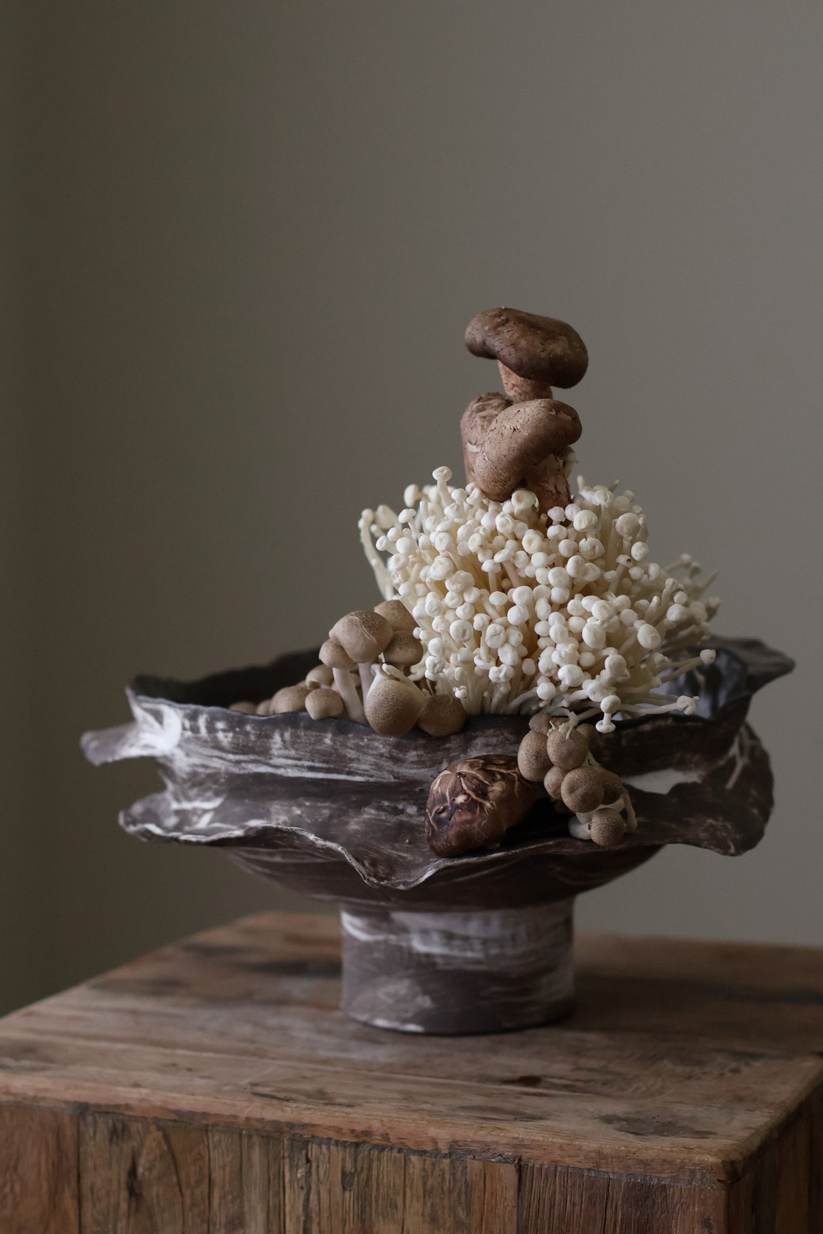 Layered Brown Pedestal Bowl is a Handcrafted ceramic piece with raw, textured dark clay finish and organic wavy rim, featuring sculptural asymmetry