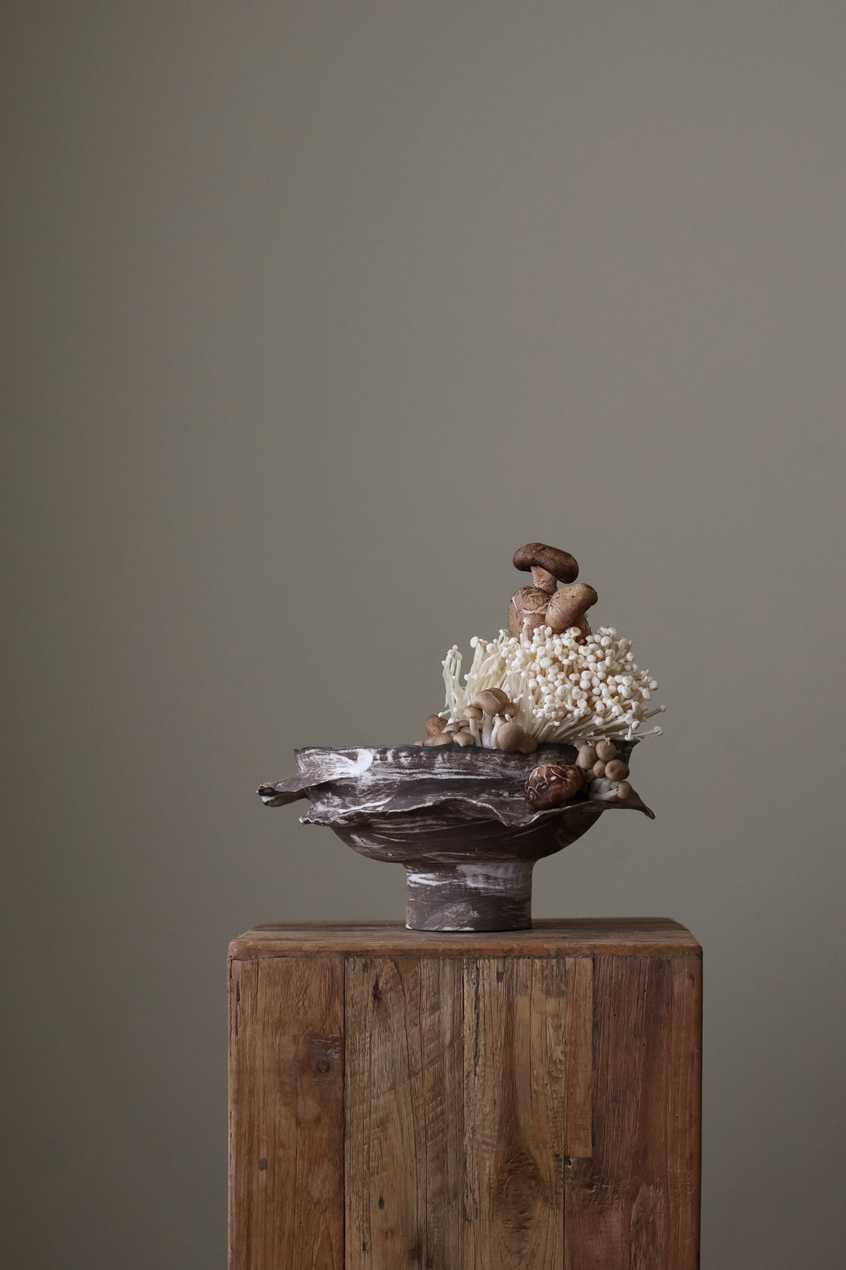 Layered Brown Pedestal Bowl is a Handcrafted ceramic piece with raw, textured dark clay finish and organic wavy rim, featuring sculptural asymmetry