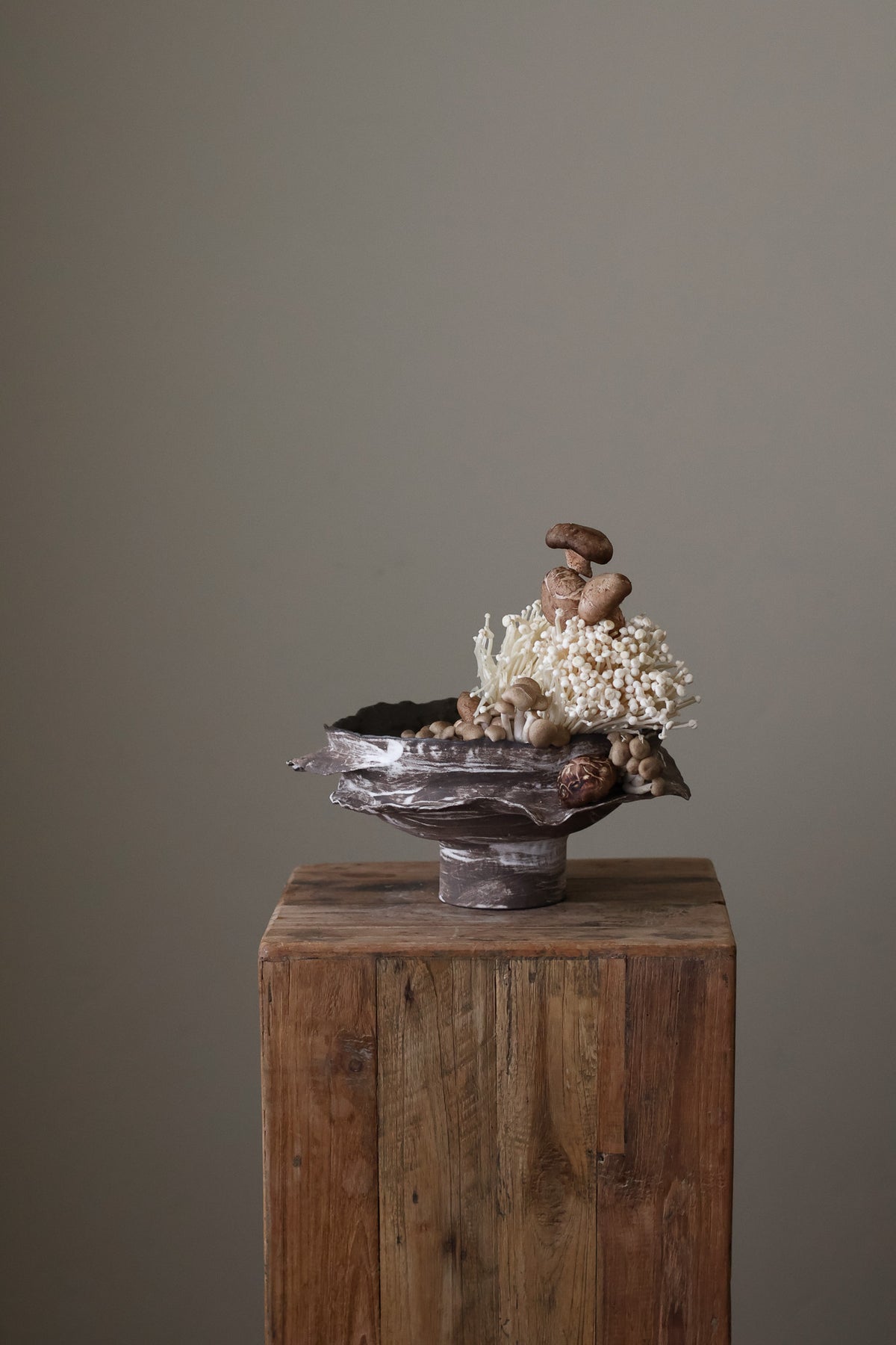 Layered Brown Pedestal Bowl is a Handcrafted ceramic piece with raw, textured dark clay finish and organic wavy rim, featuring sculptural asymmetry