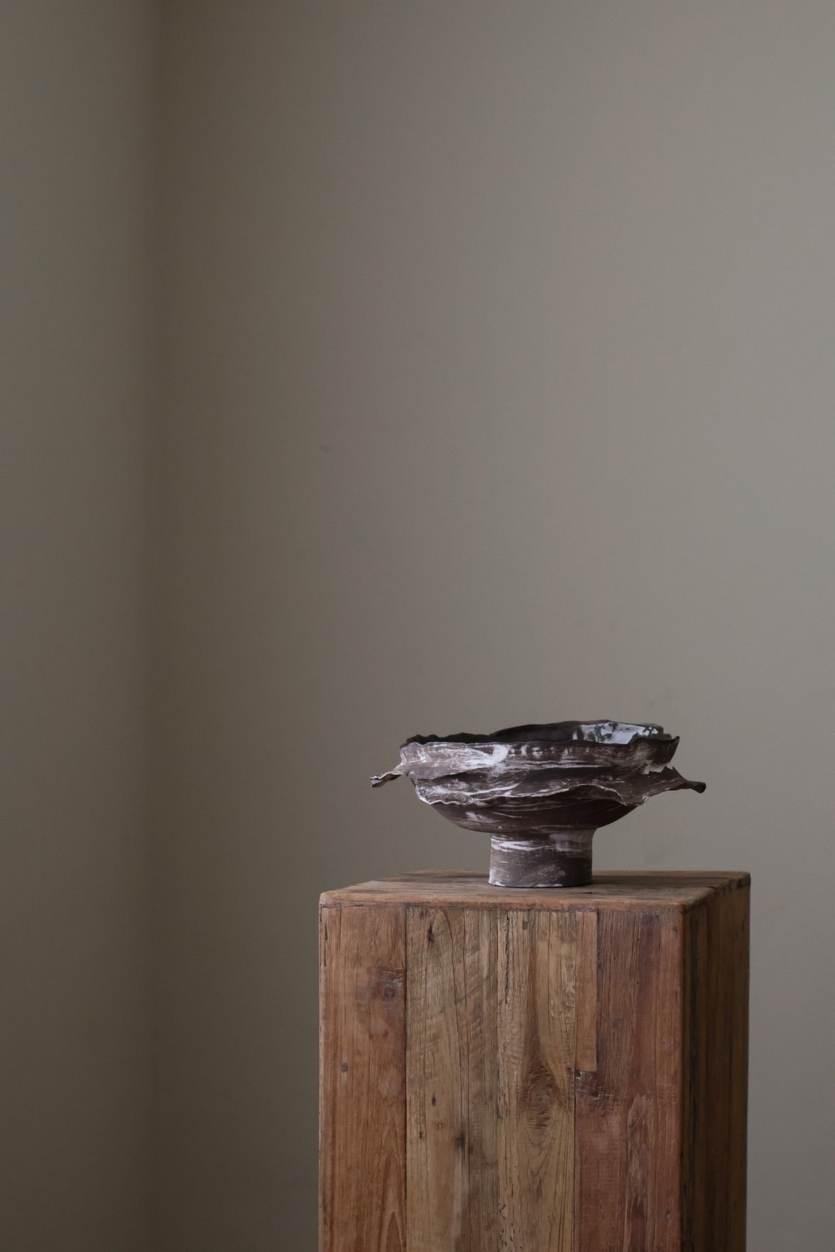 Layered Brown Pedestal Bowl is a Handcrafted ceramic piece with raw, textured dark clay finish and organic wavy rim, featuring sculptural asymmetry