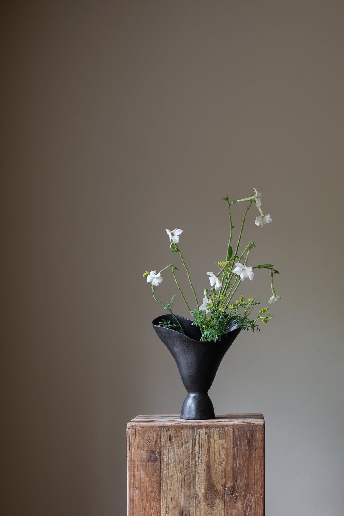 The Aires Sculptural Vessel INK by Karen Quirion, featuring fluid curves and a textured black exterior, creating a romantic yet modern aesthetic. Perfect for floral arrangements and as a striking interior centerpiece.