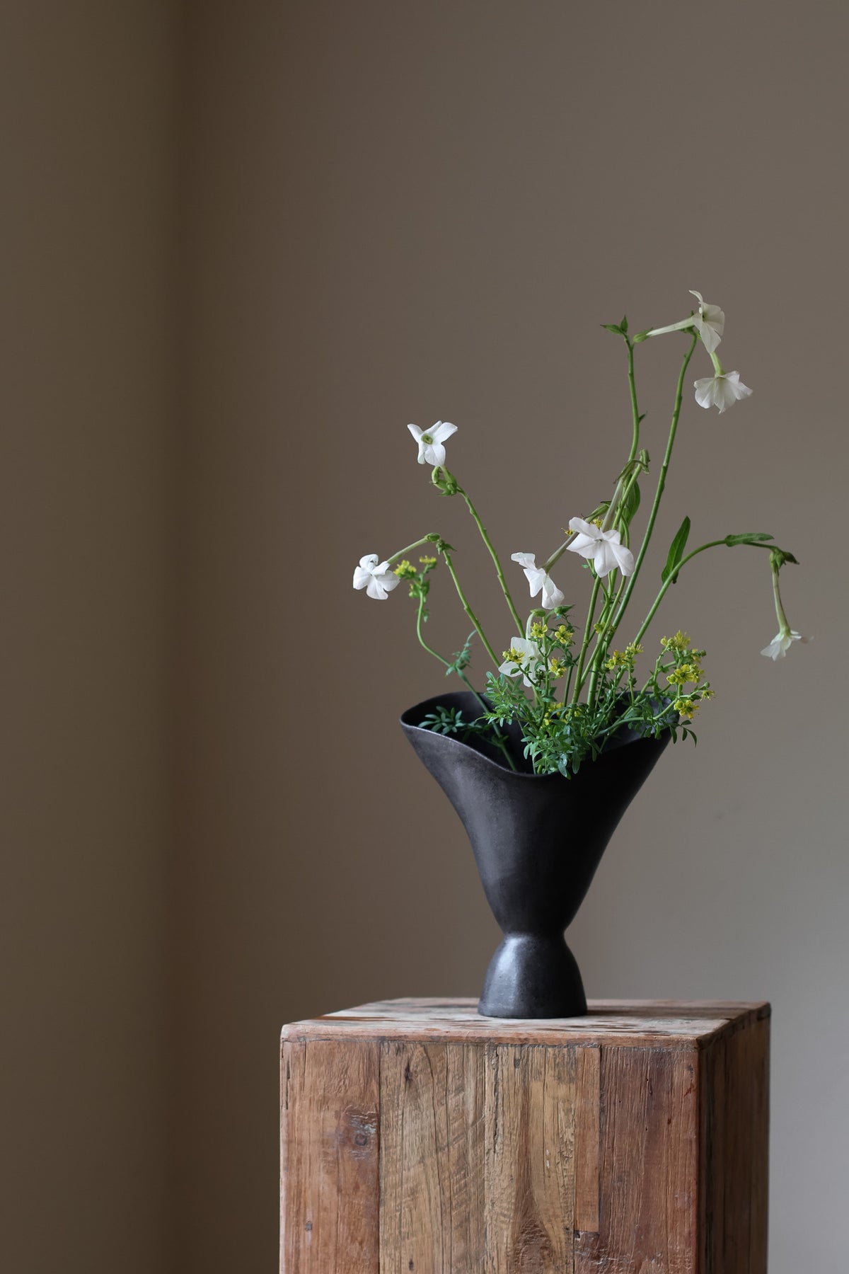 The Aires Sculptural Vessel INK by Karen Quirion, featuring fluid curves and a textured black exterior, creating a romantic yet modern aesthetic. Perfect for floral arrangements and as a striking interior centerpiece.