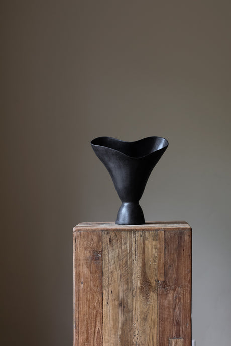 The Aires Sculptural Vessel INK by Karen Quirion, featuring fluid curves and a textured black exterior, creating a romantic yet modern aesthetic. Perfect for floral arrangements and as a striking interior centerpiece.