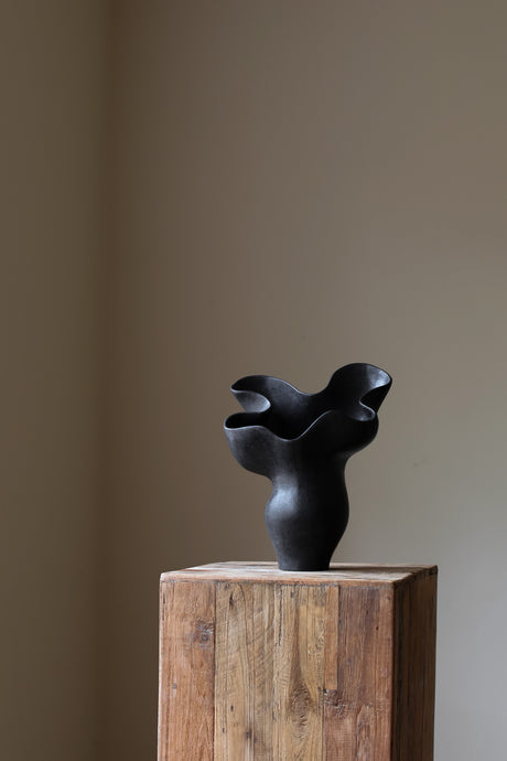 The Spur Sculptural Vessel by Karen Quirion, featuring five rounded petals and sharp, geometric angles in a deep charcoal hue. A blend of brutalist influence and refined elegance.
