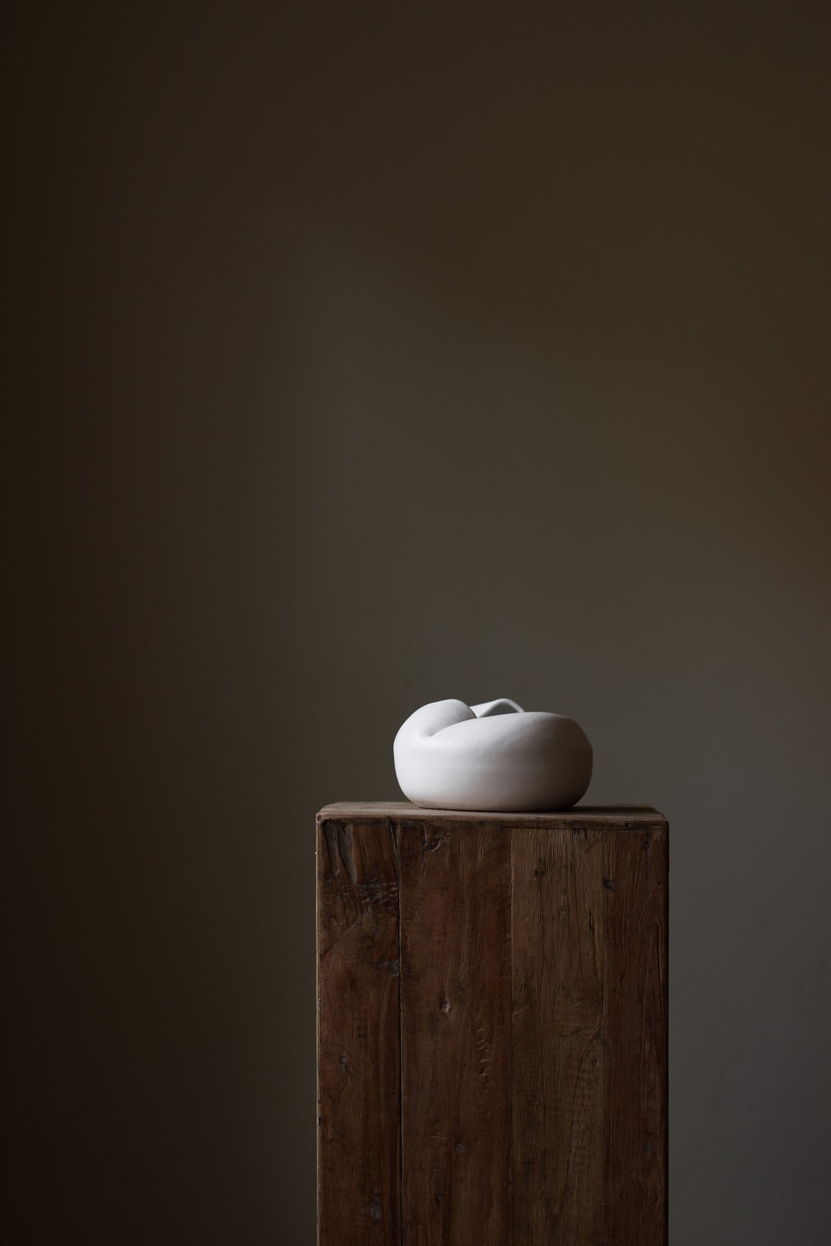 Sculptural white porcelain vase with fluid form and distinctive fold dividing it into asymmetrical halves, modern centerpiece.