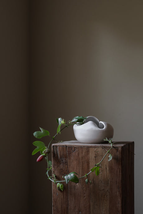 Sculptural white porcelain vase with fluid form and distinctive fold dividing it into asymmetrical halves, modern centerpiece