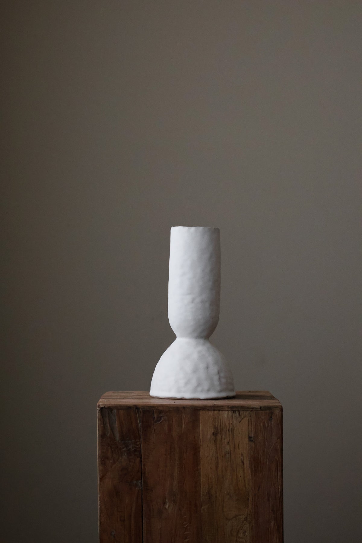Modern sculptural vase in bright white, featuring a distinctive, textured surface and a simple, cylindrical form with a slightly flared base.