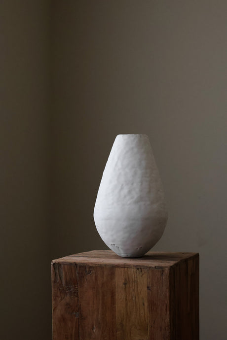 Hand-built, tall, white ceramic vase with a heavily textured surface and a slightly bulbous, rounded form. 