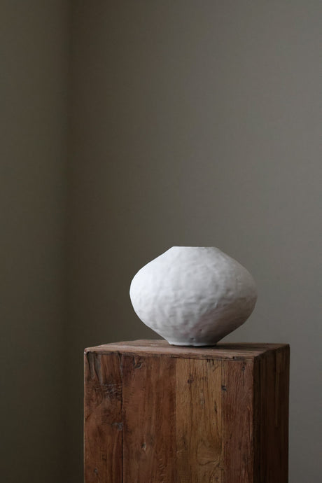 Hand-built white sculptural vase with a heavily textured, organic surface and a slightly irregular, rounded form. 