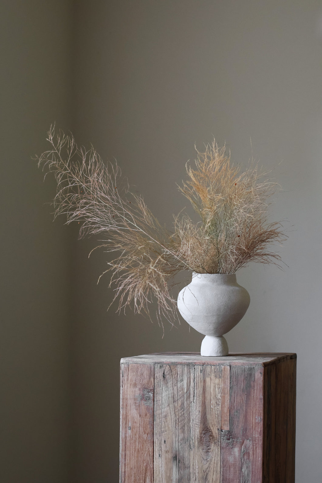 A hand-built, matte white sculptural vase by Hana. The vase features a generously rounded, almost bulbous body that tapers dramatically to a slender, short neck. The surface of the vase exhibits a subtle, textured quality, suggesting the artist's hand-building process.  