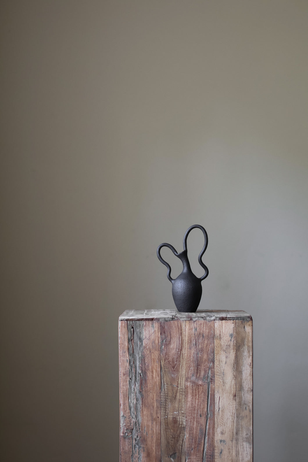 Hand-built dark ceramic vase with a textured, matte finish and two dramatically looped, sculptural handles. 