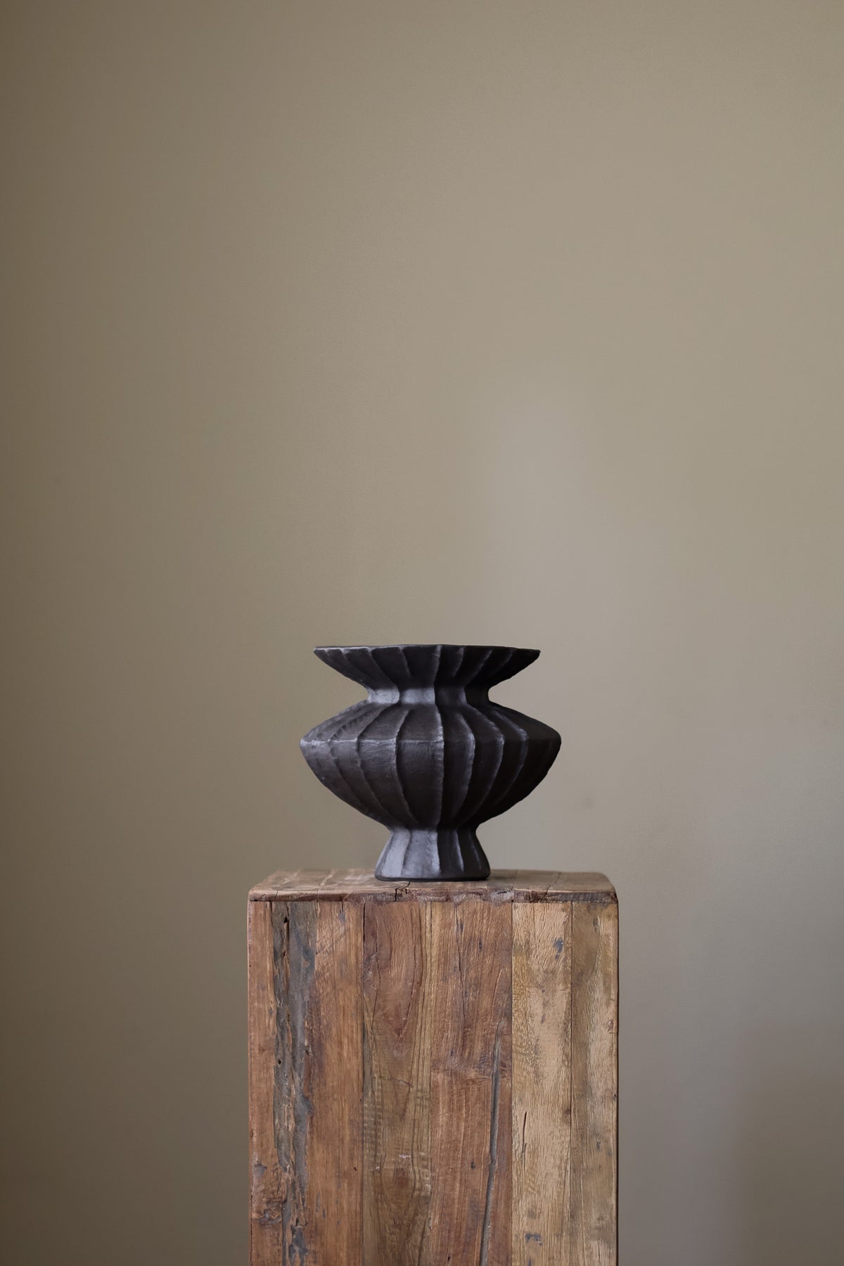 Hand-built dark ceramic vase with a rich, textured ribbed surface and a gently flared rim.