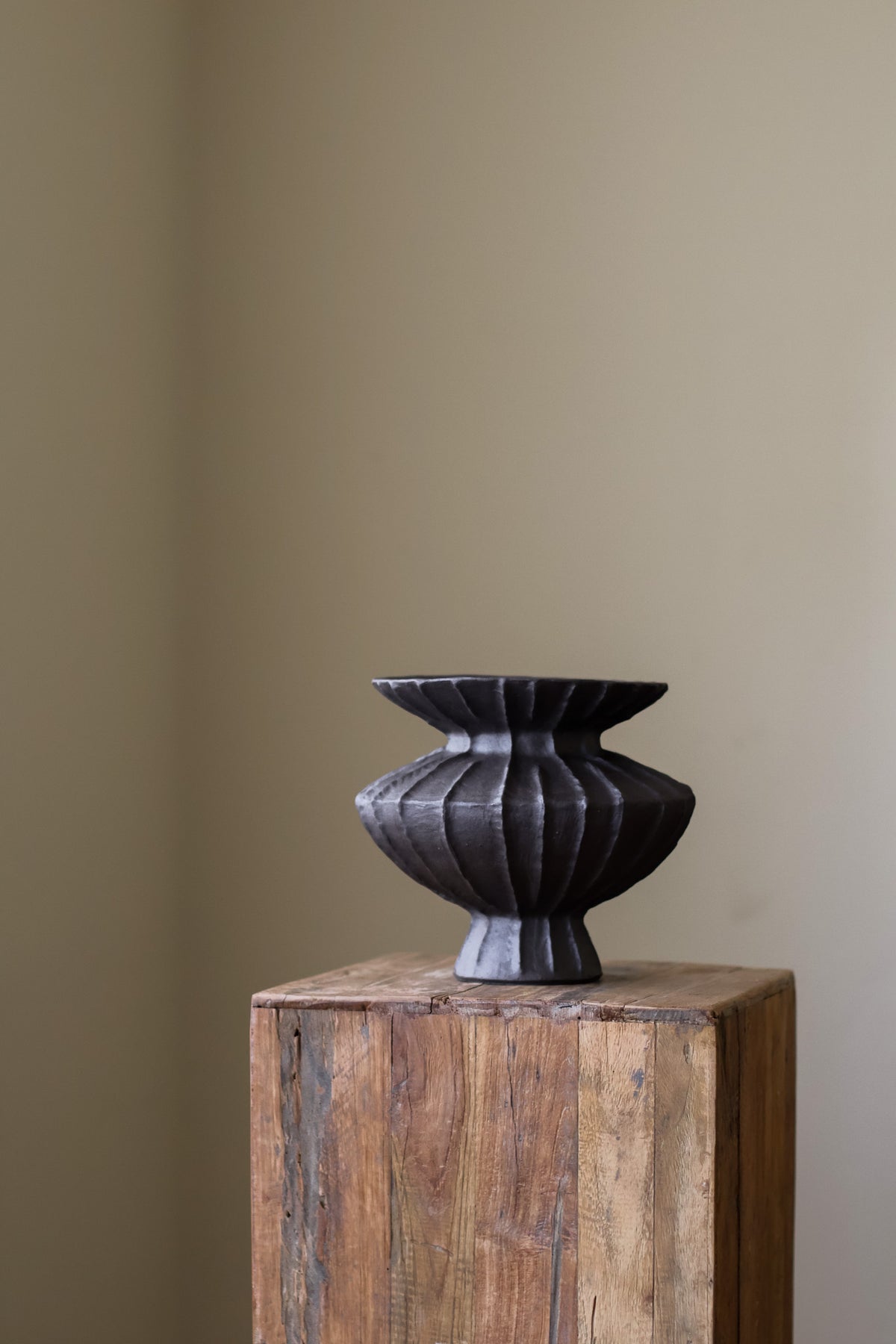 Hand-built dark ceramic vase with a rich, textured ribbed surface and a gently flared rim.