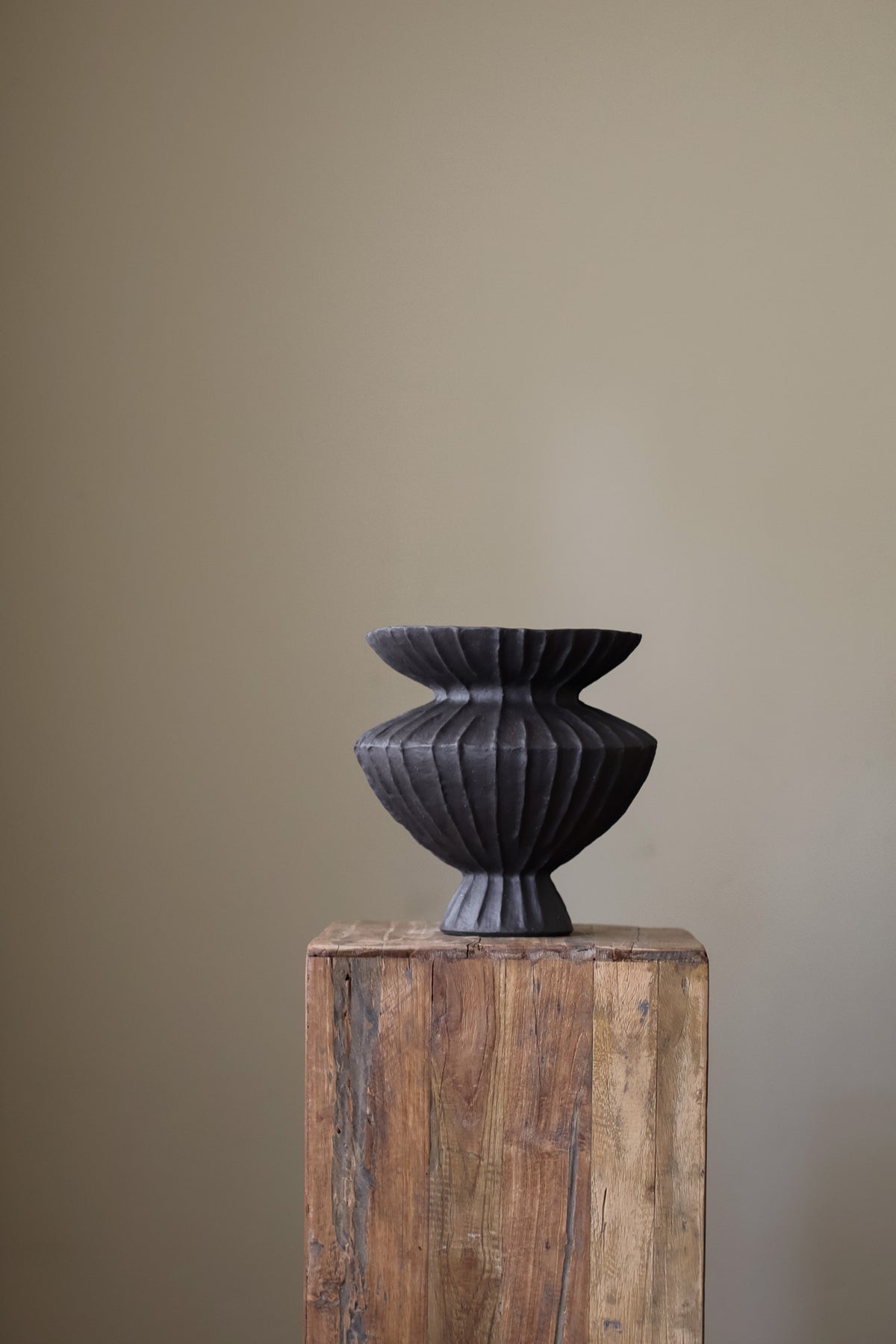Hand-built dark ceramic vase with a rich, textured ribbed surface and a gently flared rim.