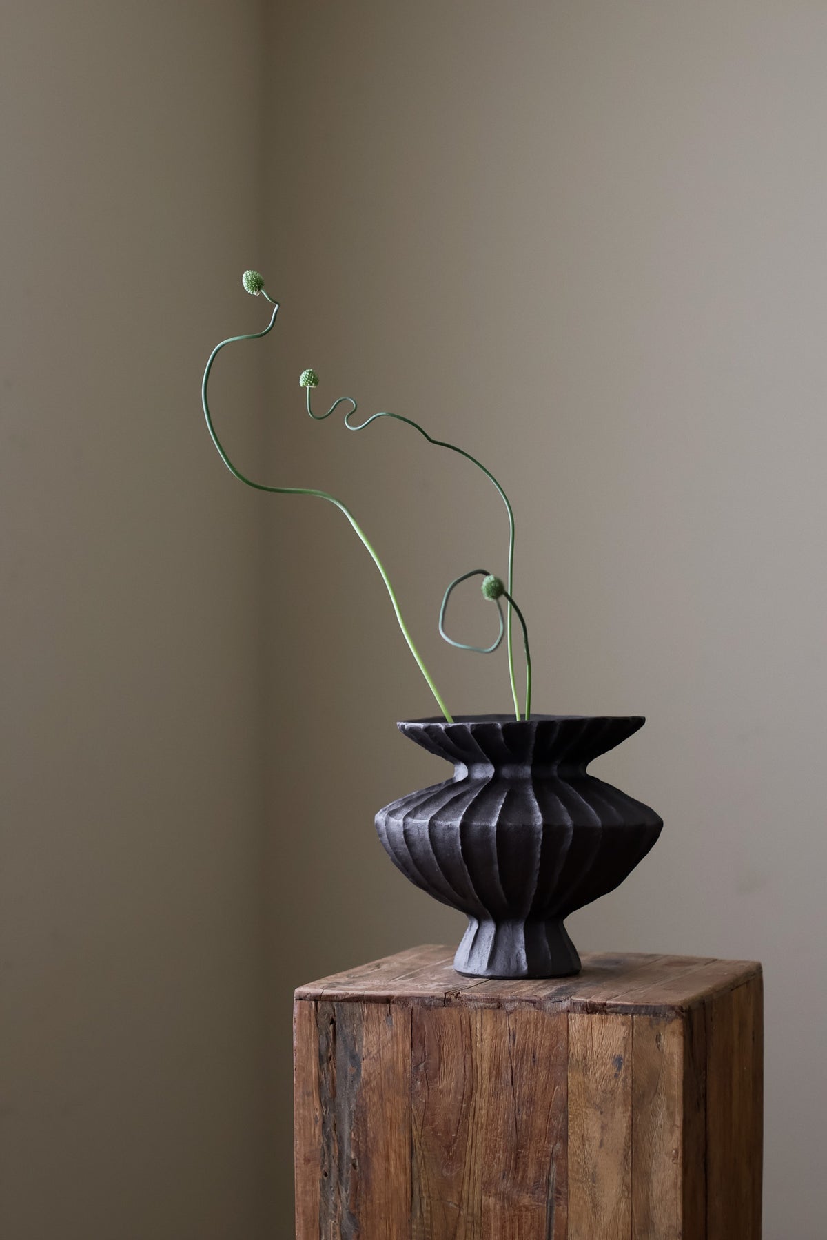 Hand-built dark ceramic vase with a rich, textured ribbed surface and a gently flared rim. 