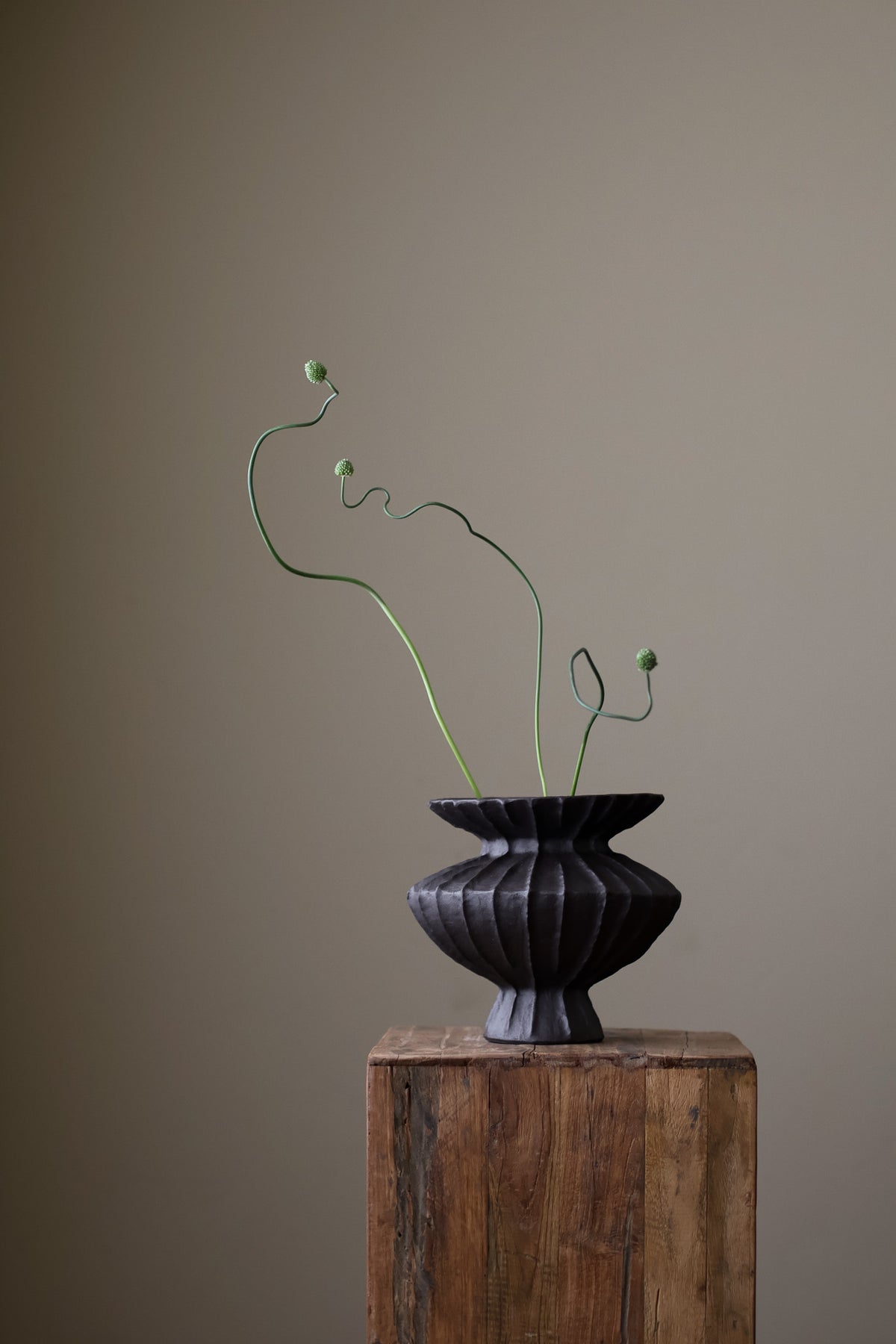 Hand-built dark ceramic vase with a rich, textured ribbed surface and a gently flared rim. 