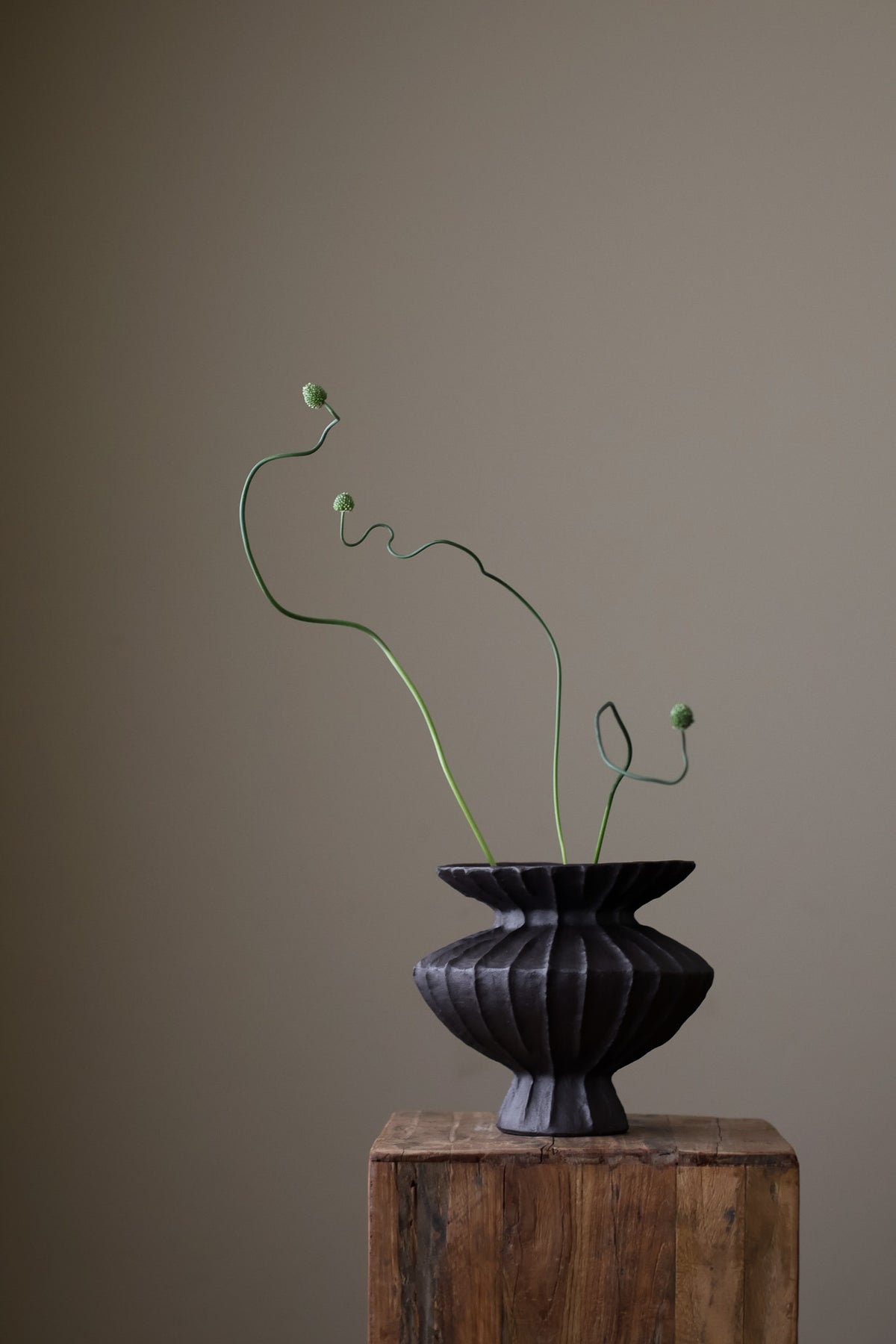 Hand-built dark ceramic vase with a rich, textured ribbed surface and a gently flared rim.